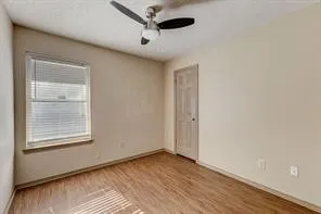Room featuring wood-finish flooring, a ceiling fan with integrated lighting, and neutral wall tones
