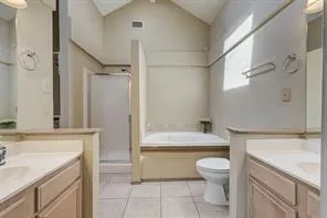 Vaulted ceiling, dual vanity, tile flooring, built-in bathtub, and enclosed shower