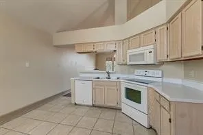 Kitchen featuring light wood-finish cabinetry, white countertops, tile flooring, an integrated microwave, and an electric range