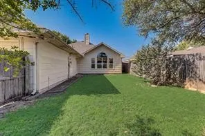 Expansive grassy yard with mature perimeter landscaping and wood fencing