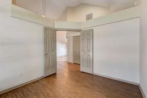 Vaulted ceiling, wood-finish flooring, paneled interior doors, and neutral wall finishes