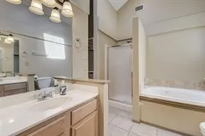 Dual vanity with integrated sinks, built-in soaking tub with tile surround, enclosed shower with frosted glass, and vaulted ceiling