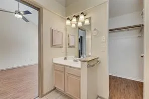 Bathroom vanity with light wood-finish cabinetry, a white countertop, and a four-light fixture
