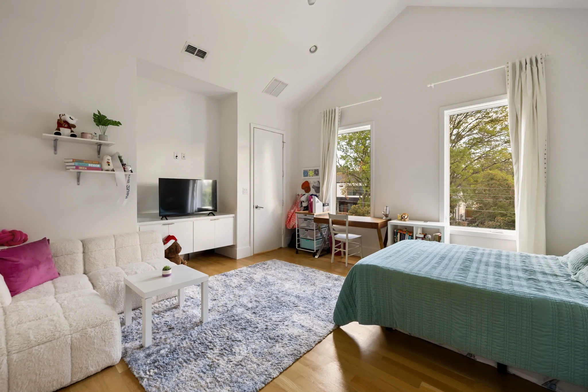 Vaulted ceiling, two tall windows, wood-finish flooring, built-in shelving, and a built-in media console