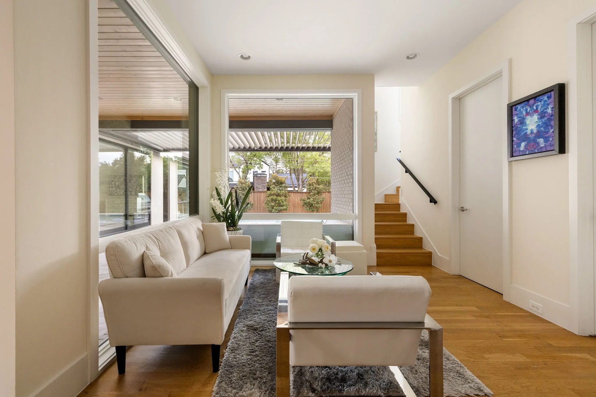 Open-concept living area with wood-finish flooring, a stone-faced fireplace, and high ceilings