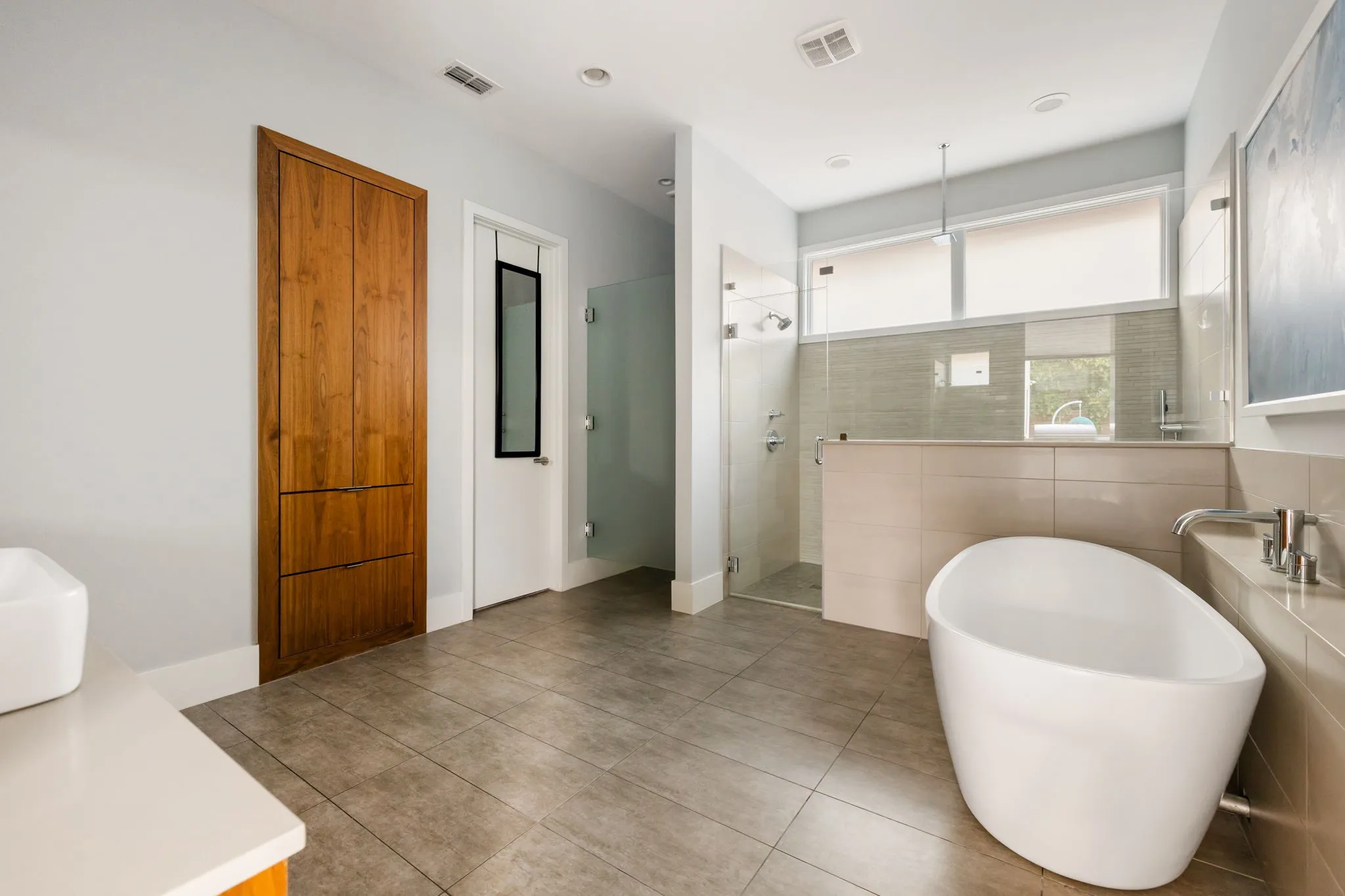 Sliding glass door opening to a concrete patio with a built-in outdoor kitchen, an in-ground swimming pool, and a louvered patio cover