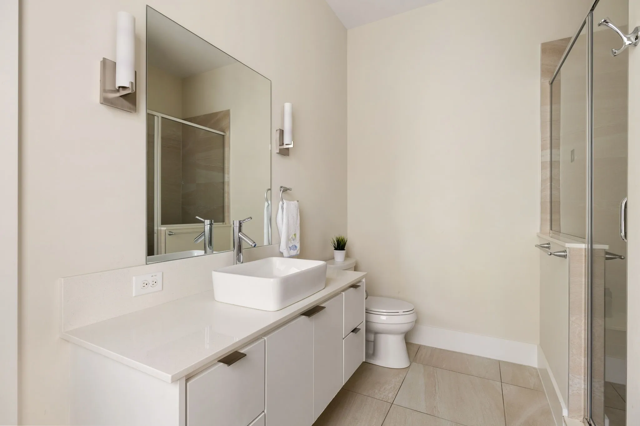 White floating vanity with a vessel sink, polished chrome fixtures, and a frameless mirror