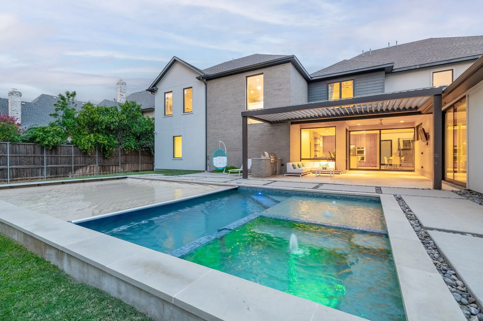 Contemporary exterior featuring a multi-level pool with integrated water features, expansive patio with a louvered pergola, and sliding glass doors