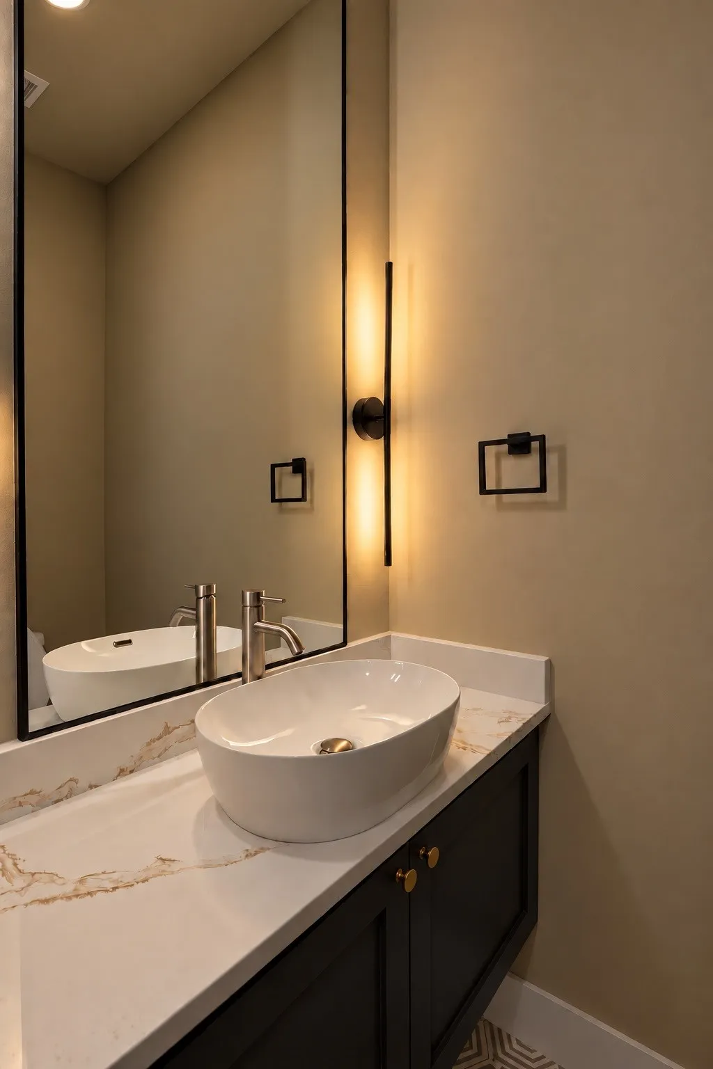 Vessel sink with a brushed nickel faucet, set on a white countertop with brown veining, above a dark vanity with gold-toned cabinet pulls