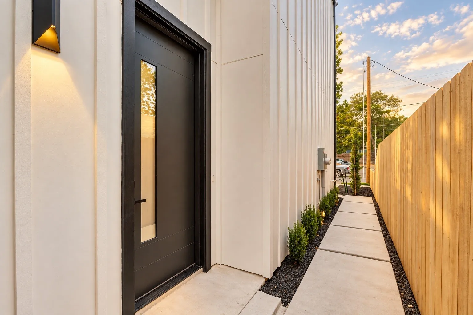 Modern exterior with vertical siding and a dark entry door featuring an integrated vertical window panel