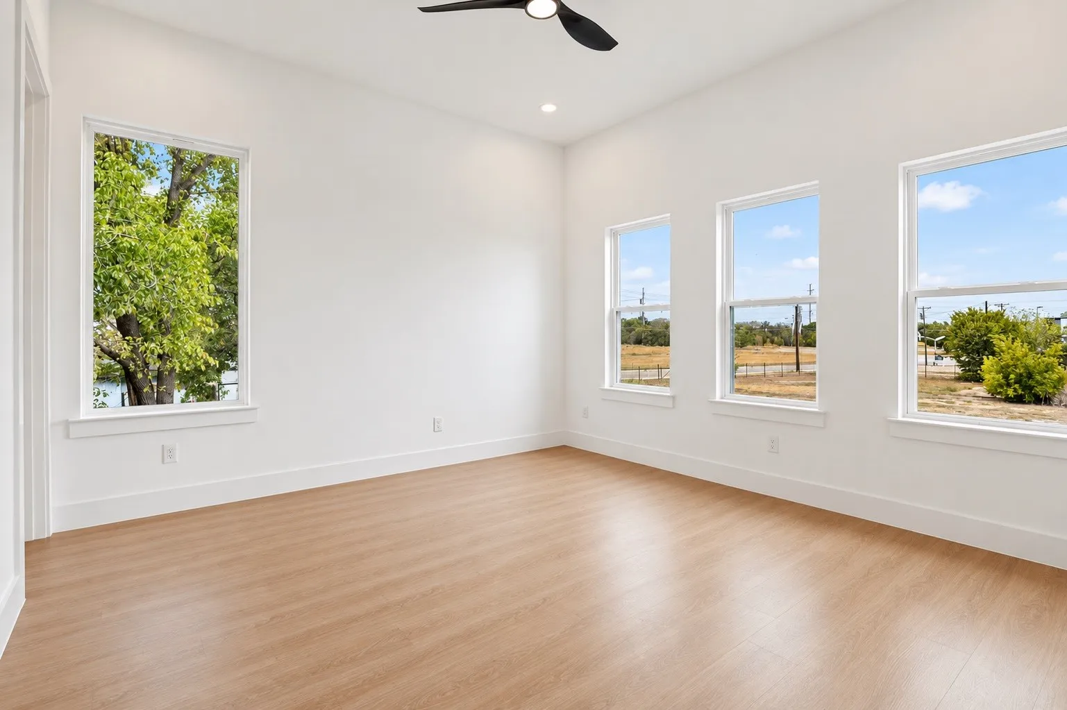 Bright interior space featuring wood-finish flooring, multiple windows, a ceiling fan, and recessed lighting