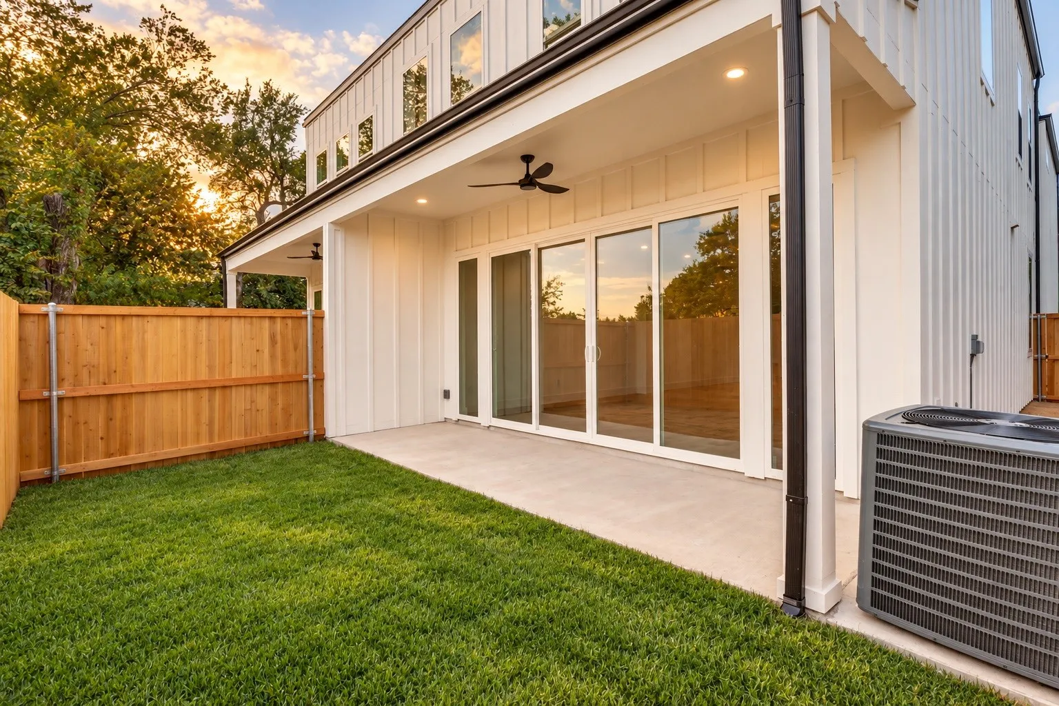 Private outdoor space featuring a fenced lawn, concrete patio, and sliding glass doors