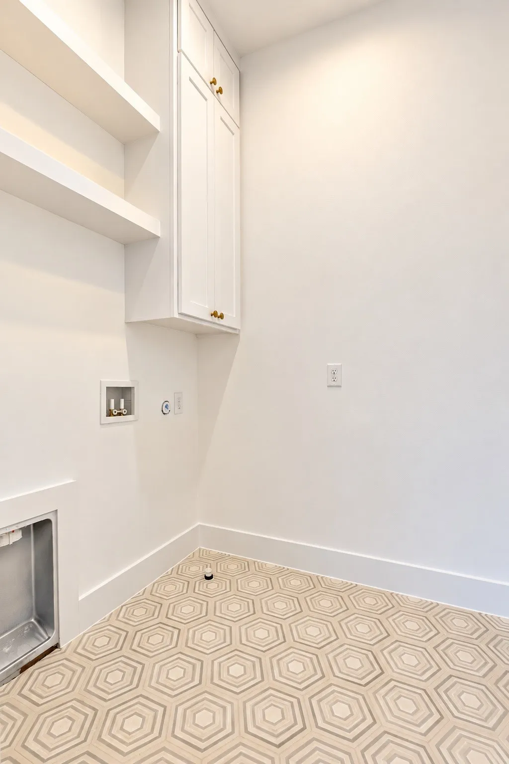 White cabinetry with gold-tone hardware, floating shelves, and geometric patterned floor tile