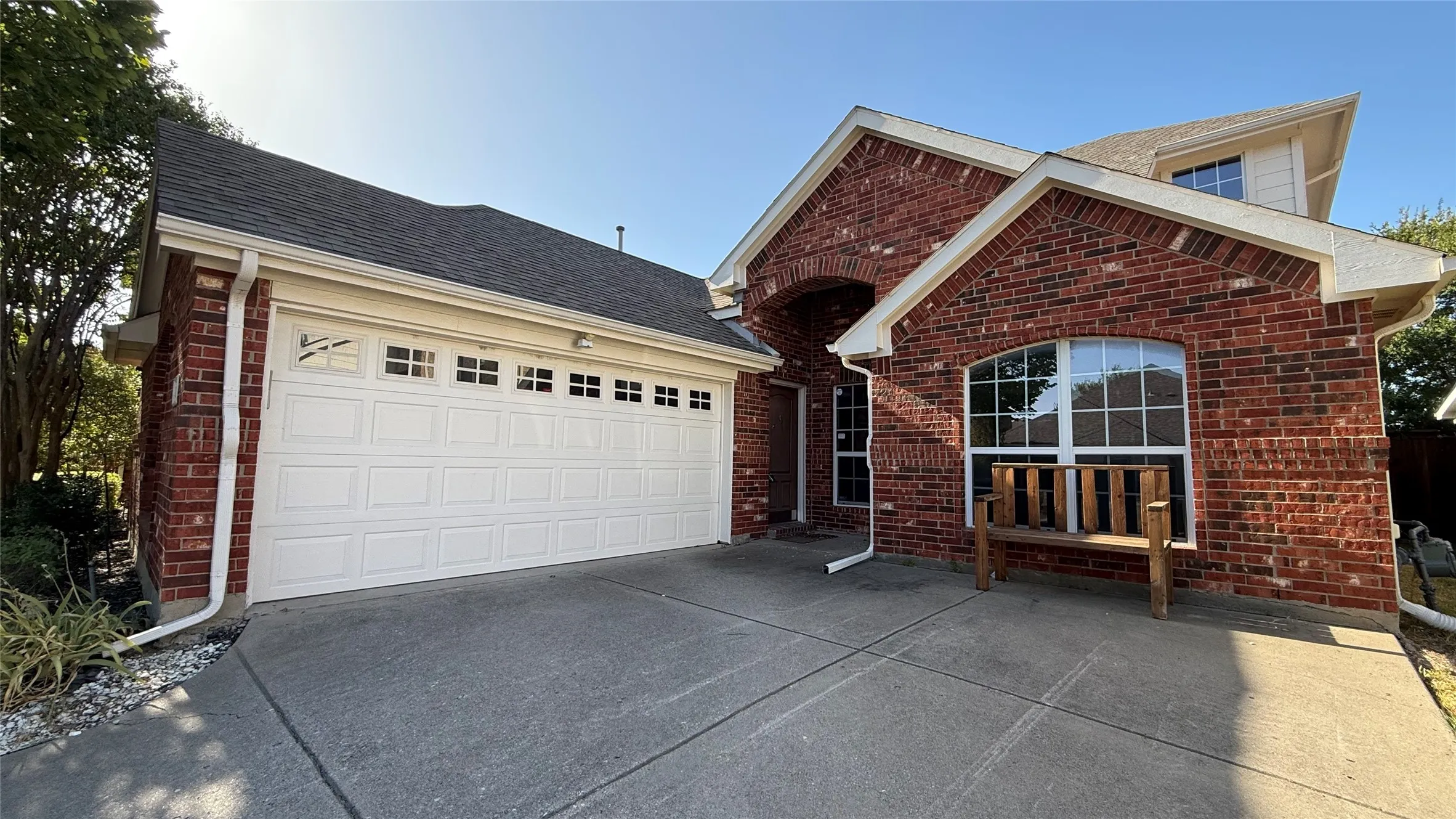 Brick exterior with white trim, arched entryway, multi-pane windows, and an attached two-car garage