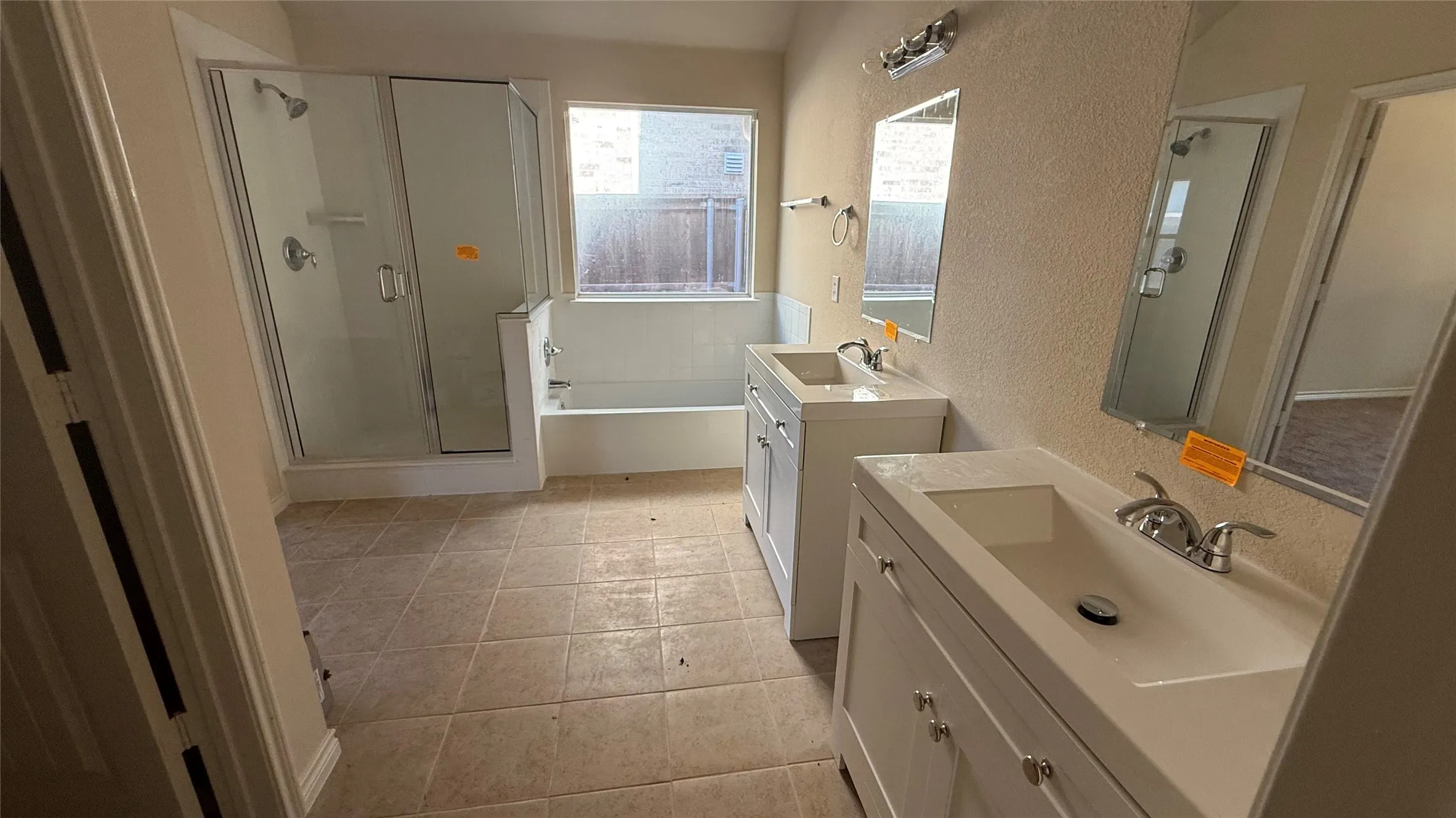 Dual vanity sinks with chrome fixtures, a built-in shower with a glass enclosure, a separate bathtub, and tile flooring