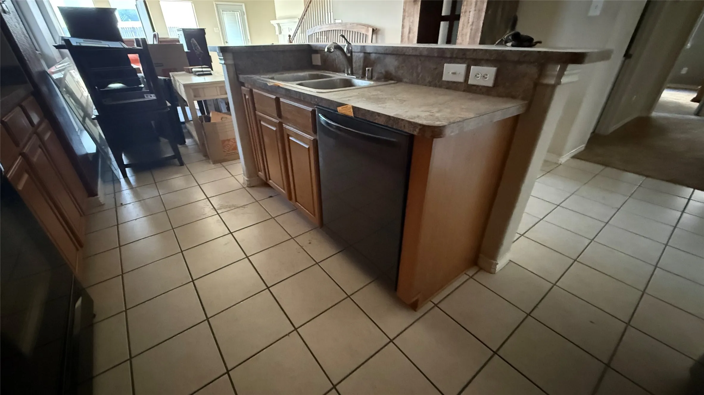 Kitchen featuring a double basin sink, dishwasher, wood-finish cabinetry, and tile flooring