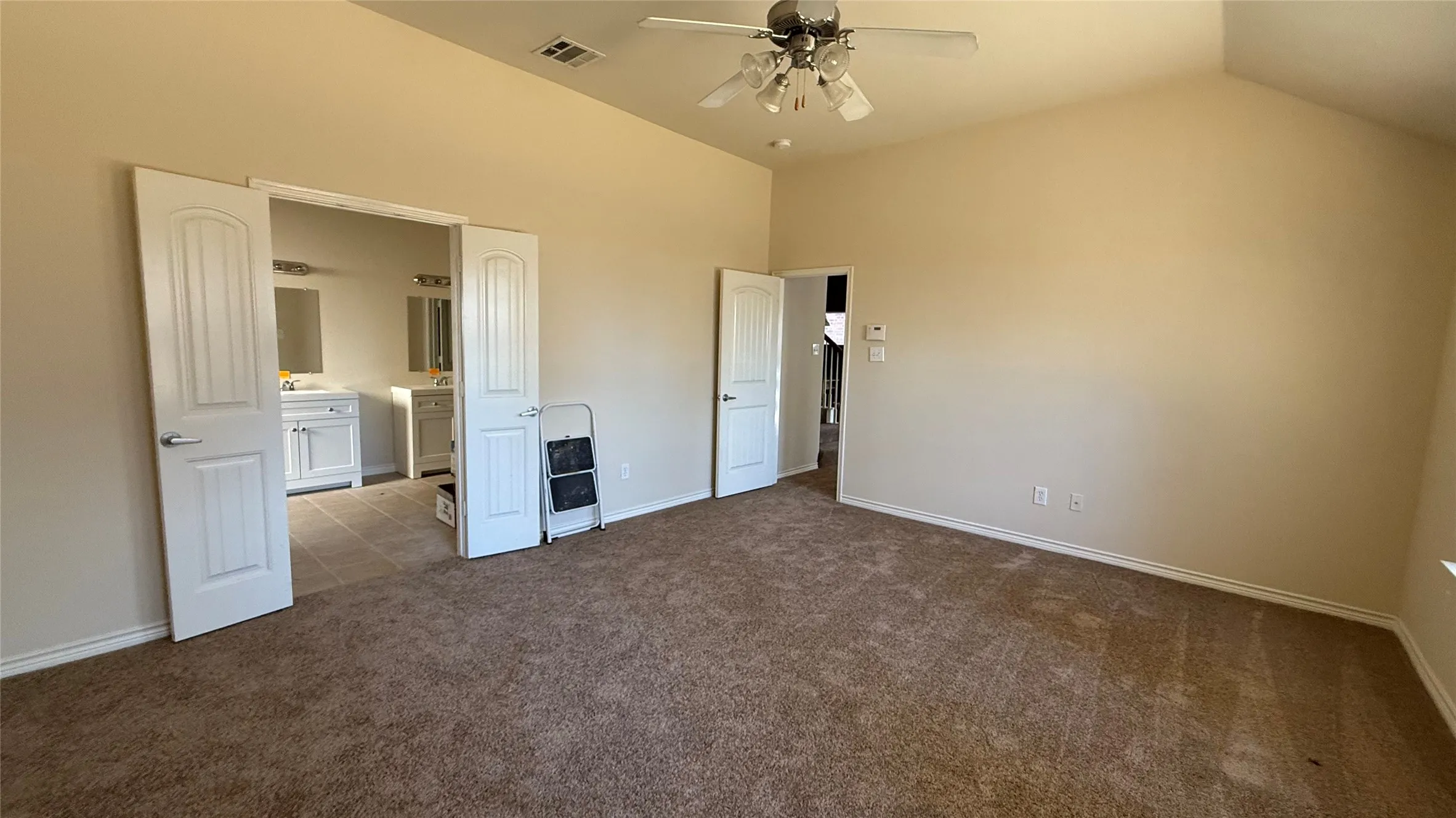 Spacious room featuring vaulted ceilings, ceiling fan, and carpeted flooring