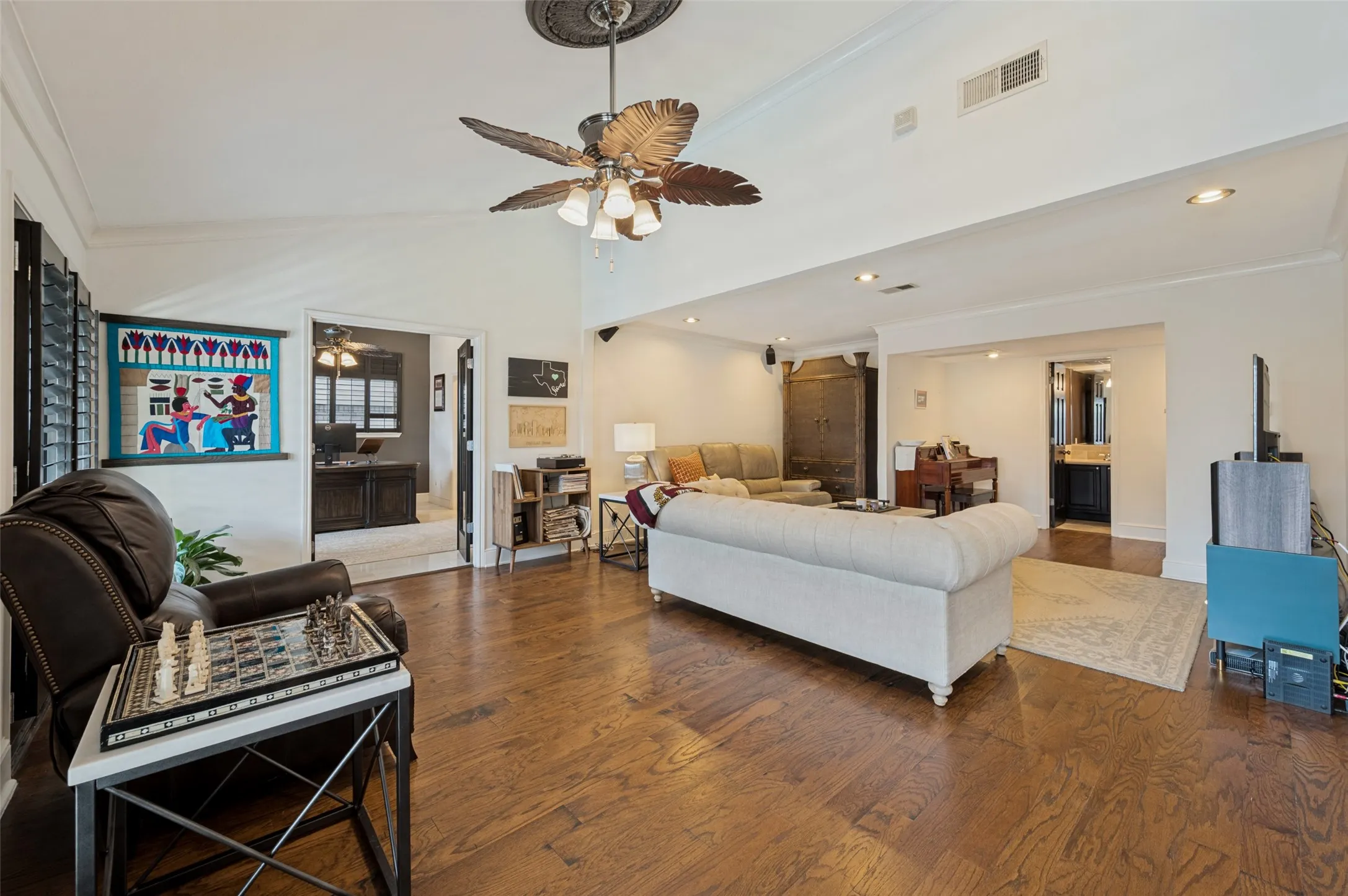 Wood-finish flooring, vaulted ceiling, decorative ceiling medallion with a ceiling fan, recessed lighting, and interior shutters