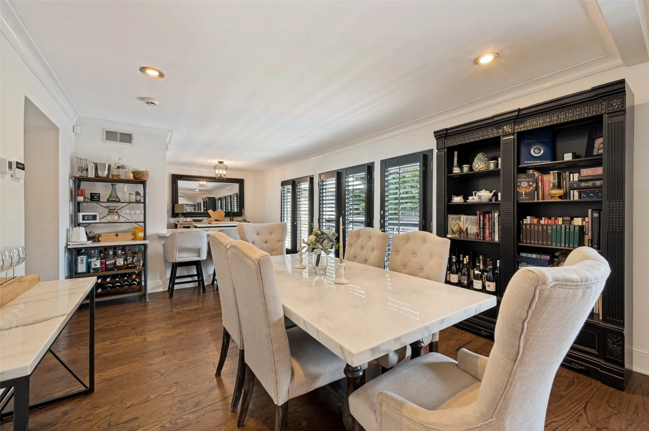 Hardwood flooring, recessed lighting, crown molding, built-in shelving, and plantation shutters