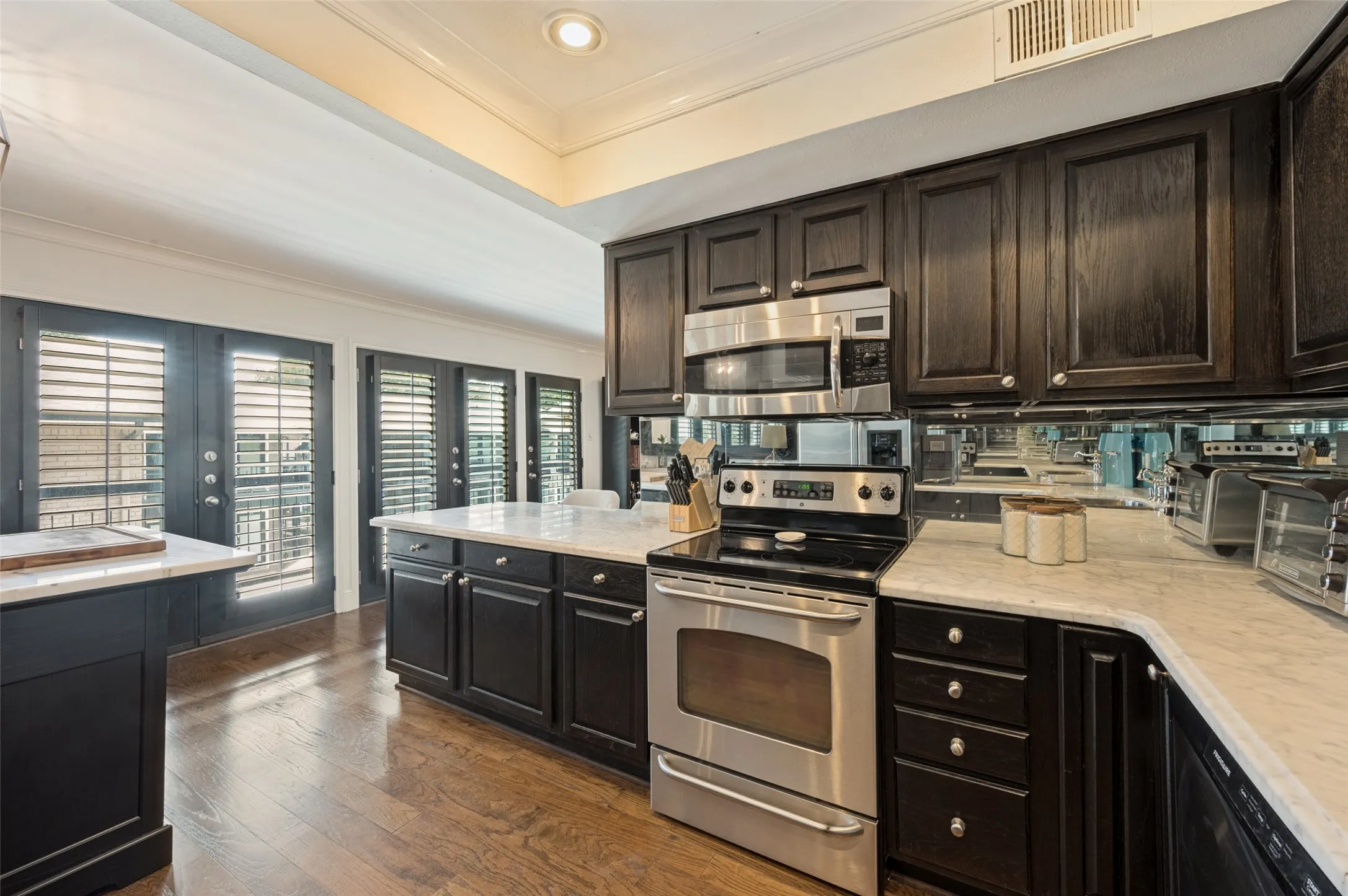 Kitchen featuring dark wood cabinetry, light-toned countertops, stainless steel appliances, and wood-finish flooring