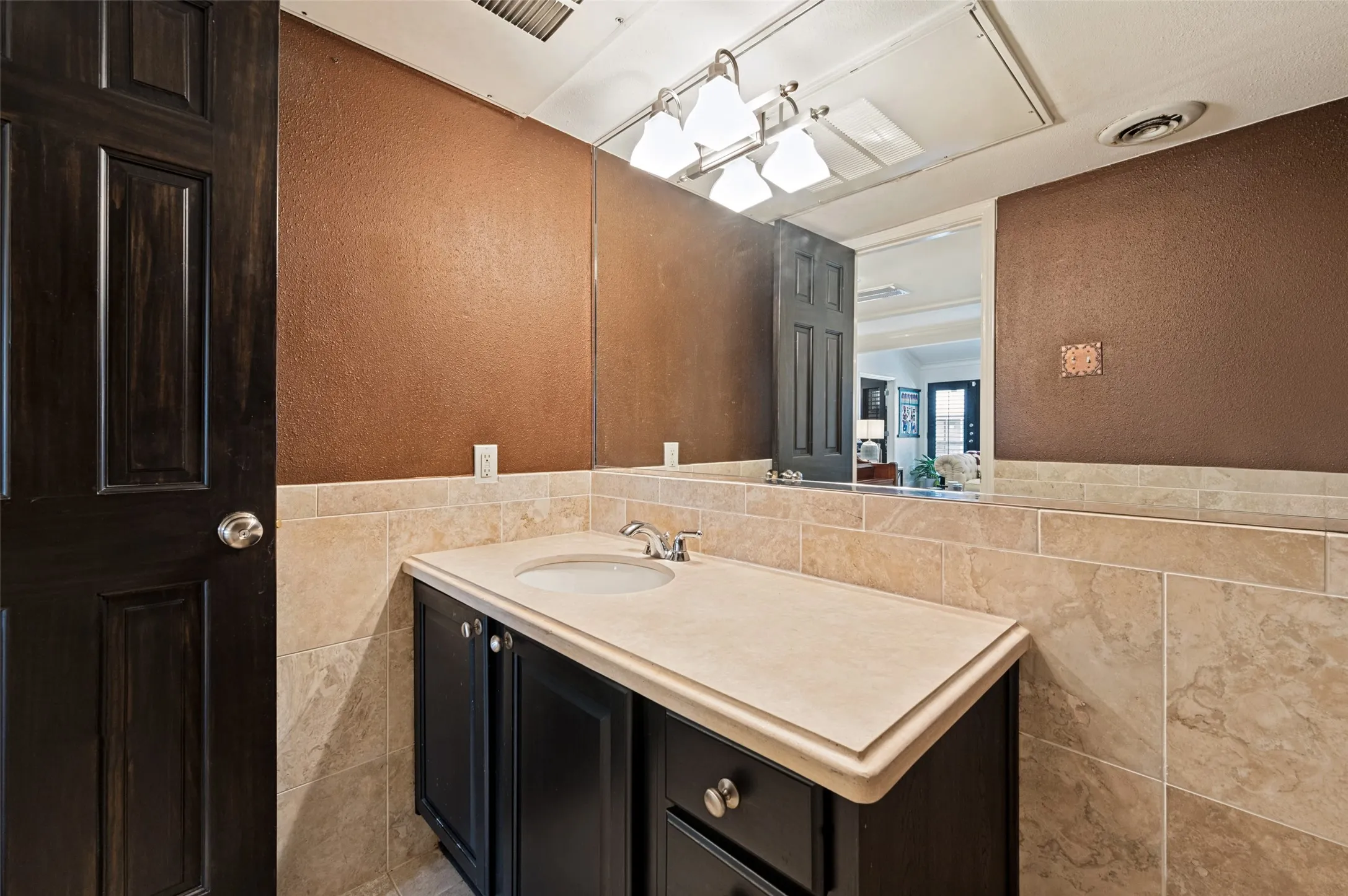 Vanity with a single basin, light-toned countertop, dark wood-finish cabinetry, and chrome hardware