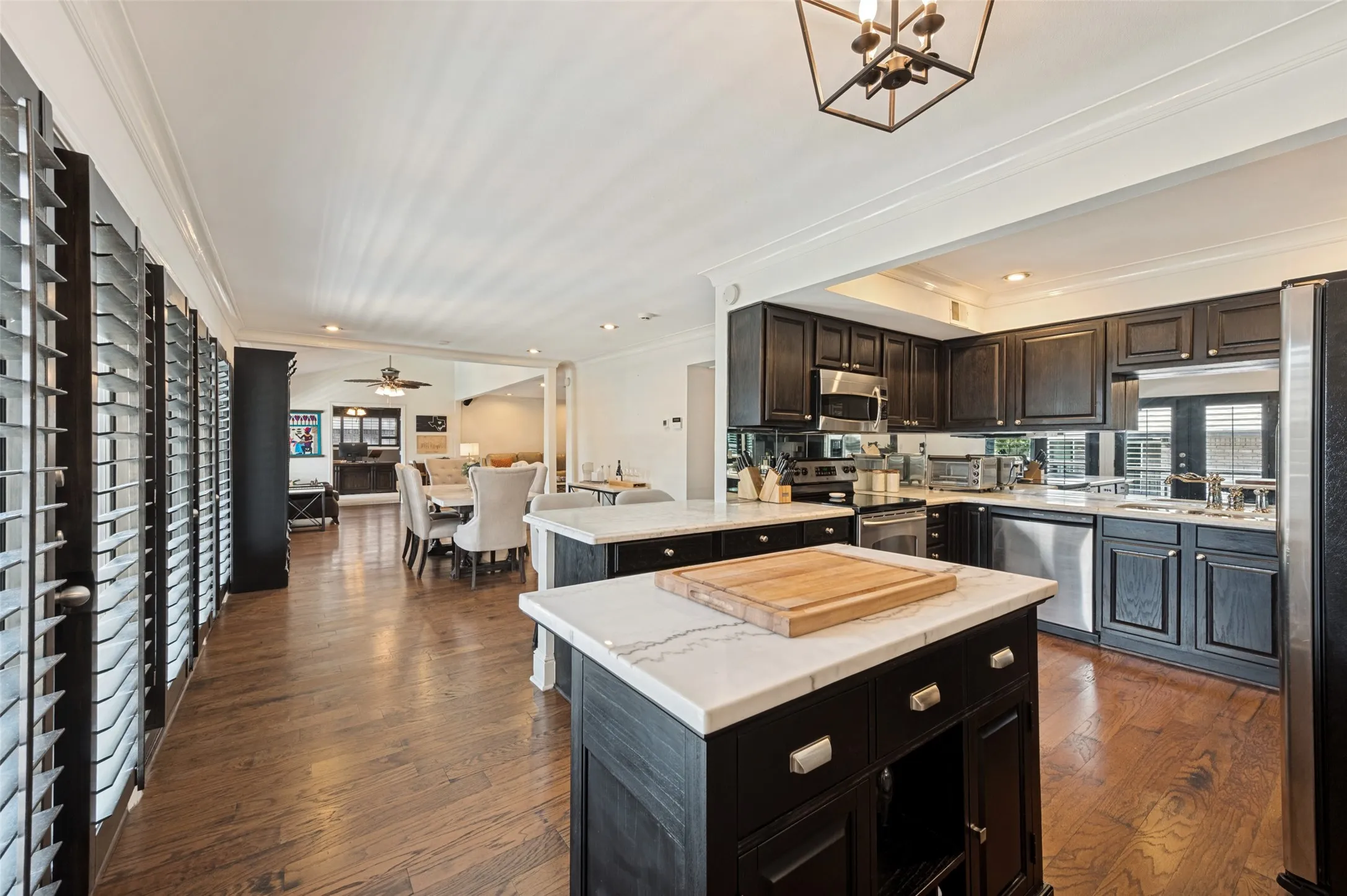 Kitchen with dual islands featuring stone countertops, dark wood cabinetry, stainless steel appliances, and wood-finish flooring