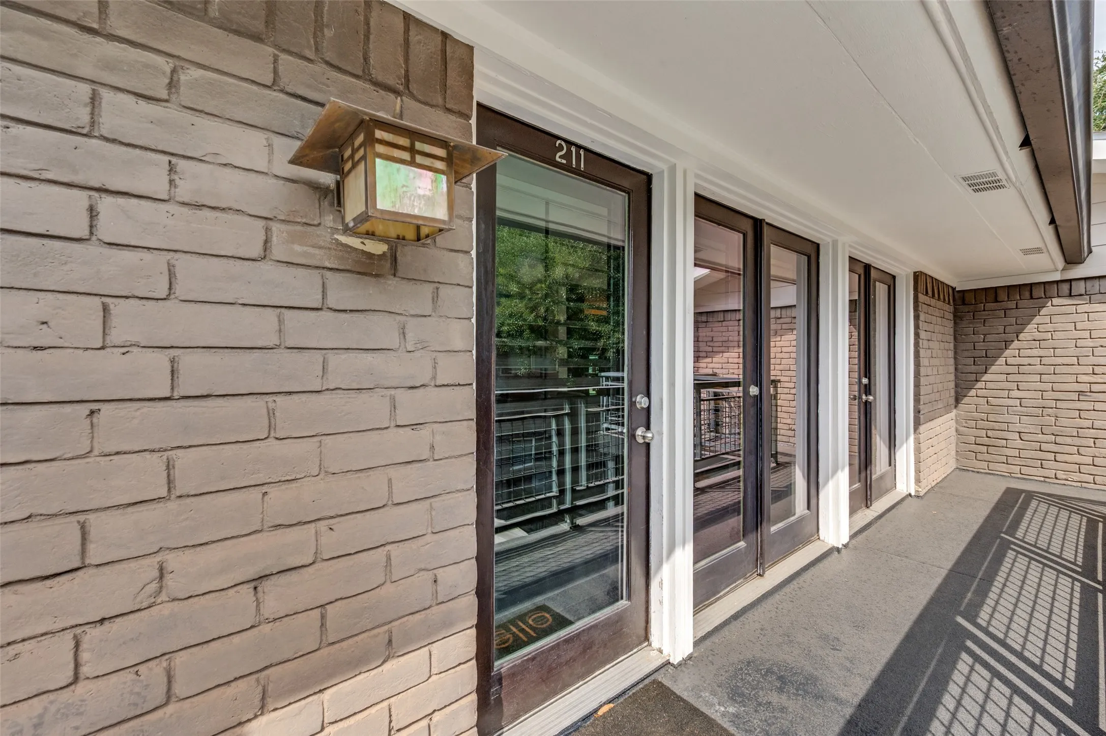 Light-colored brick exterior with multiple glass-paned doors featuring dark frames