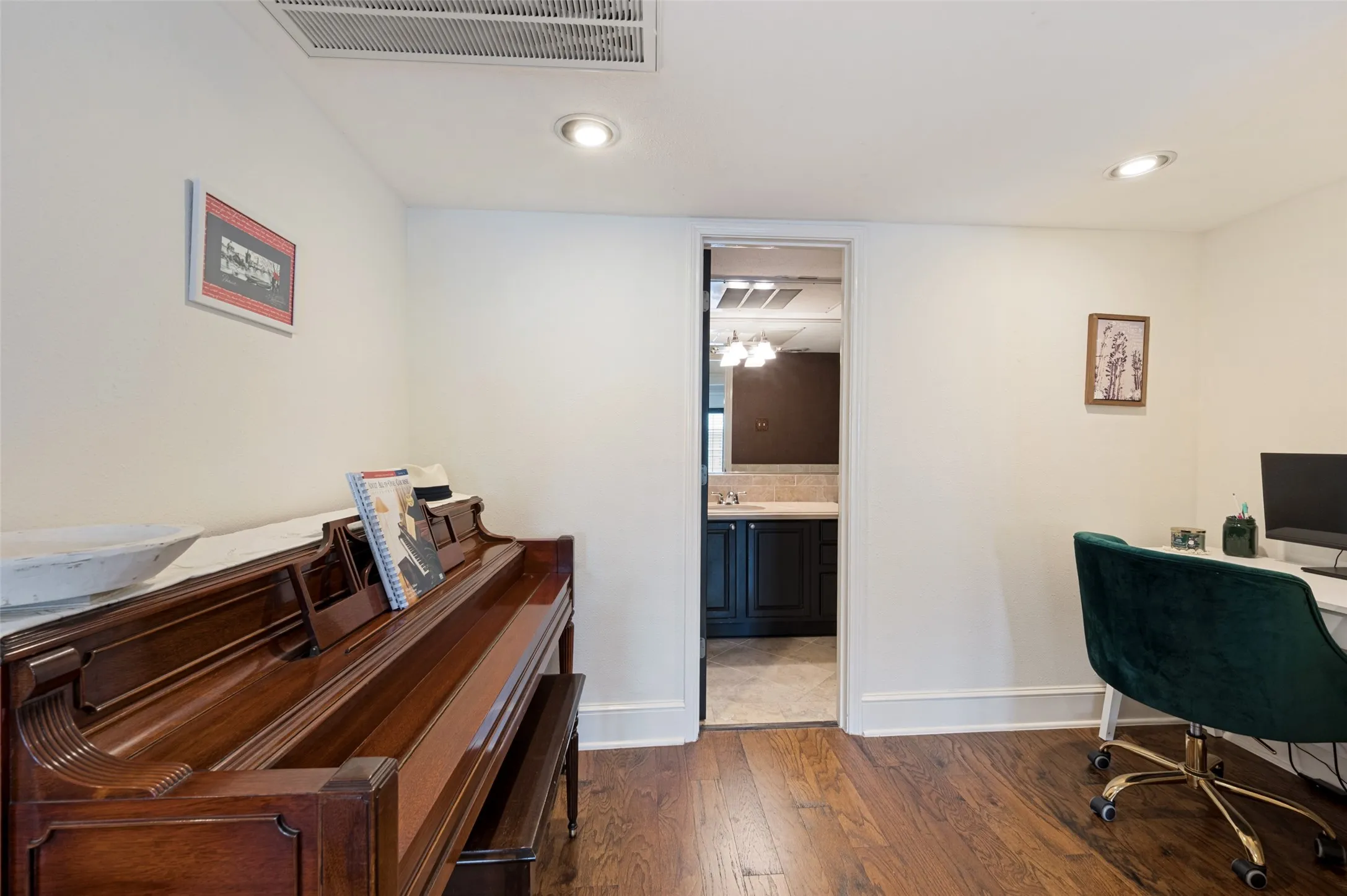 Hardwood flooring, recessed ceiling lighting, crown molding, and a built-in vanity with a stone-finish countertop