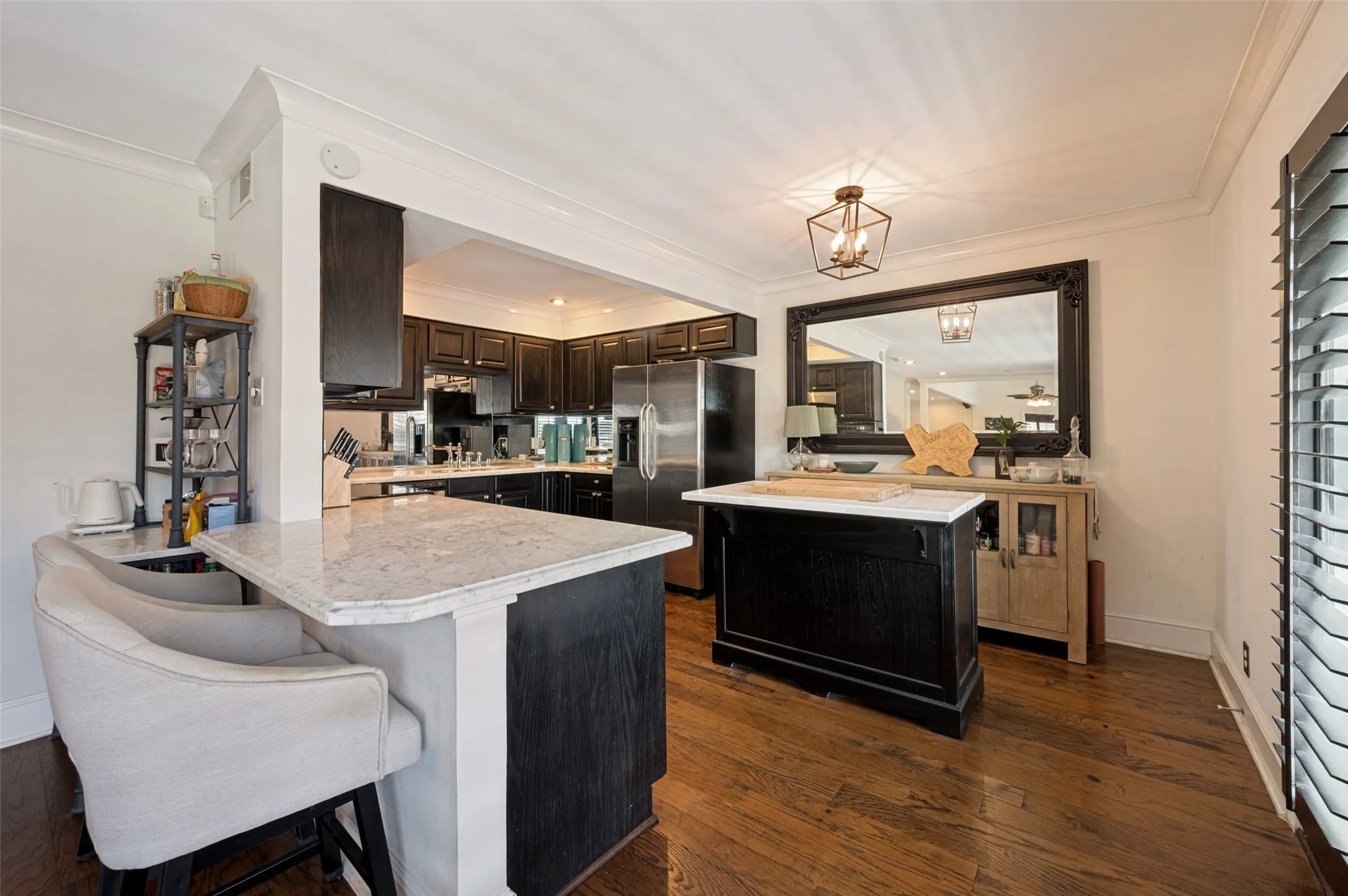 Kitchen featuring dark wood cabinetry, light-toned countertops, hardwood flooring, and a central island