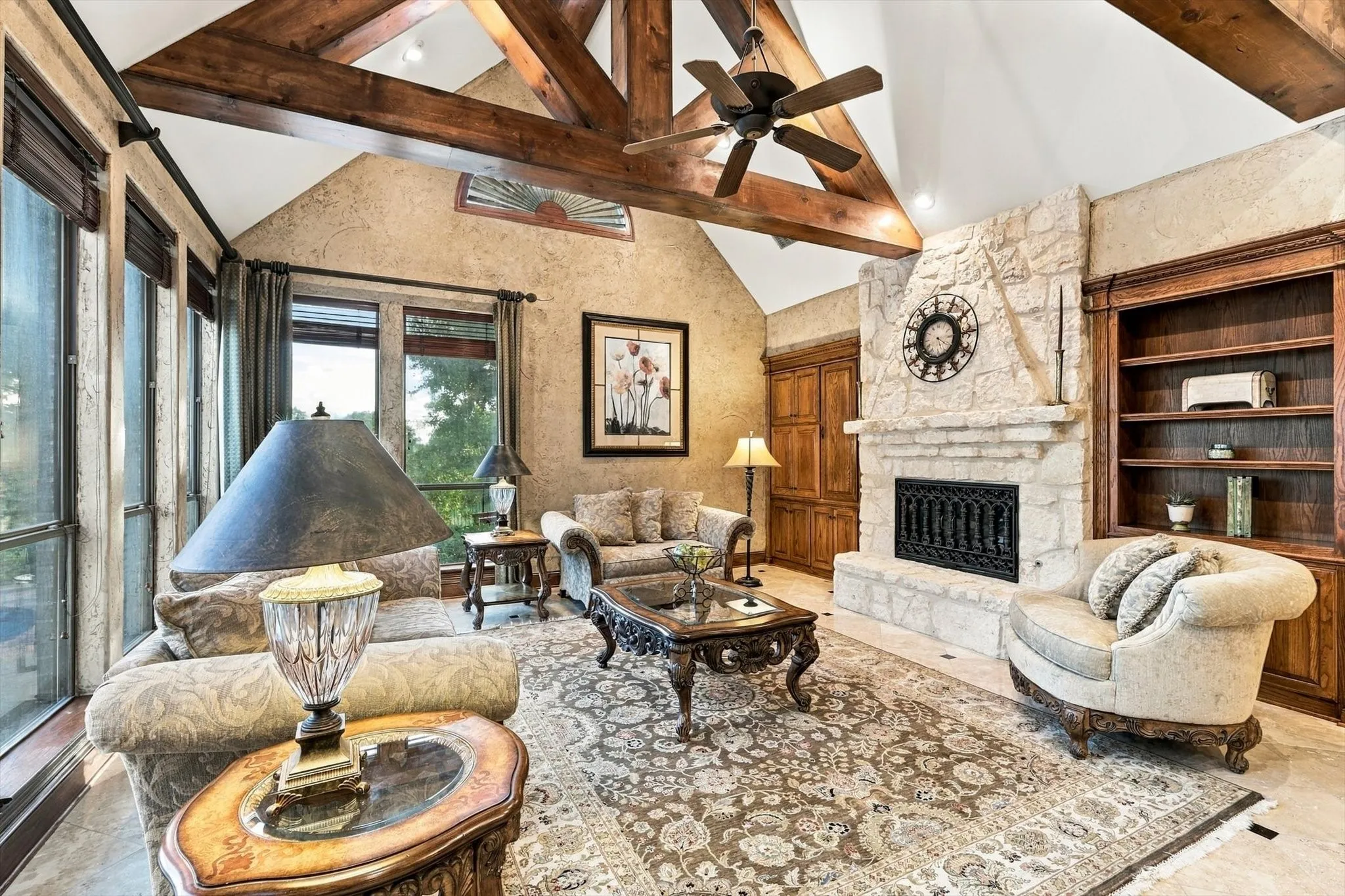Rich in character and custom details, the great room features a beautiful stone fireplace, built-in bookcases and timeless travertine floors, creating a warm and inviting gathering space.