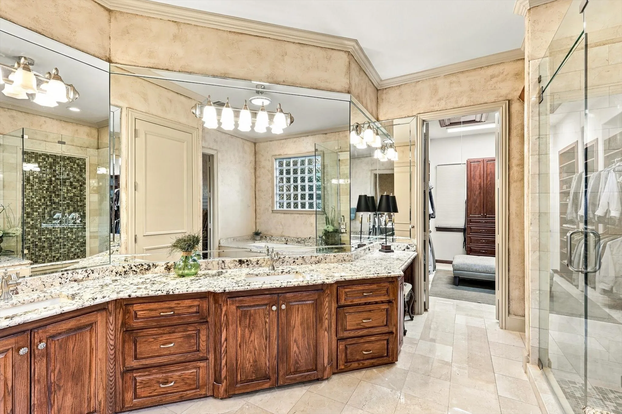 A spacious primary bath pairs dual sinks and granite countertops with an oversized closet featuring custom built-ins, creating a beautiful and highly functional retreat.