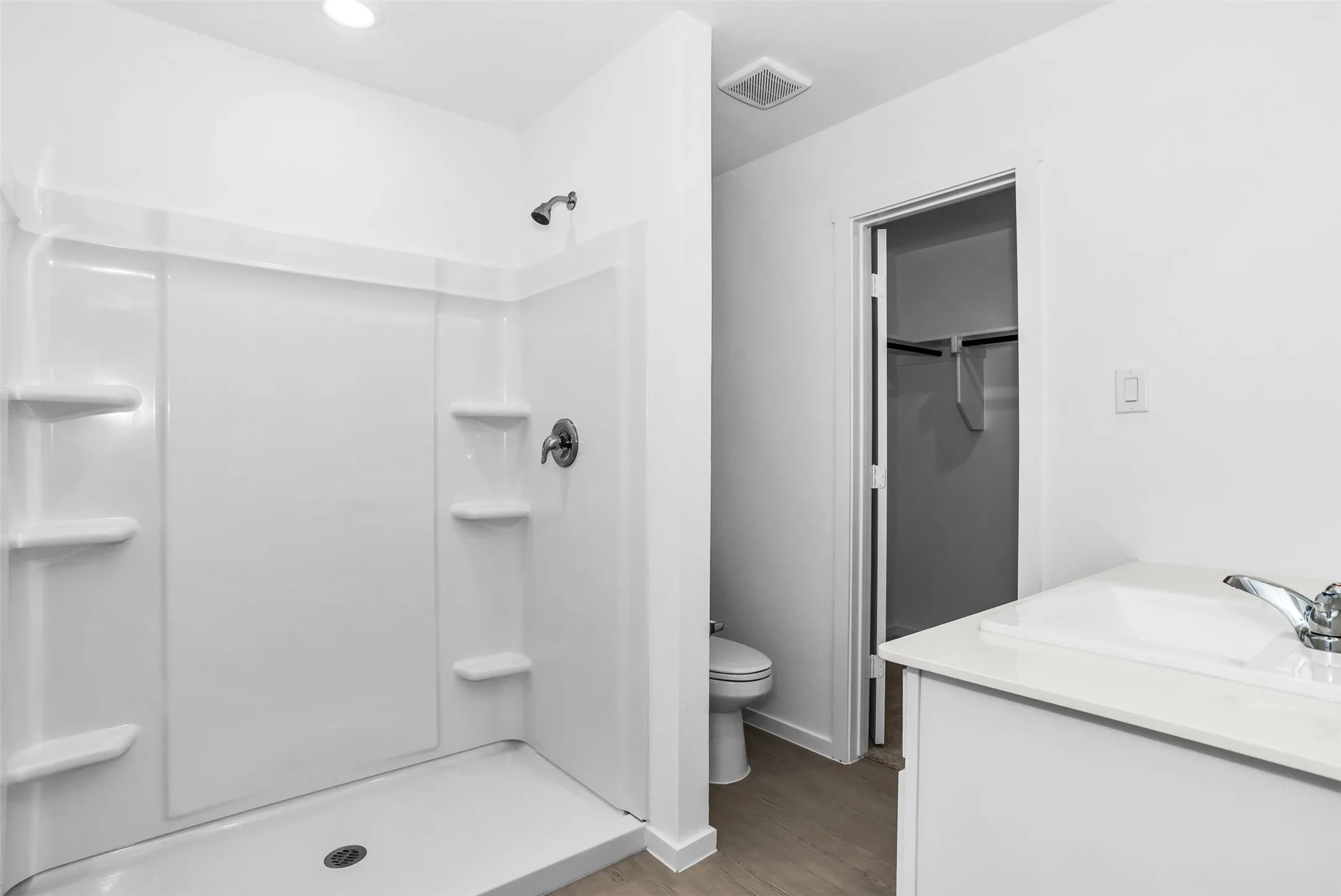 Full bathroom featuring a spacious closet, vanity, a shower stall, light wood-type flooring, and recessed lighting