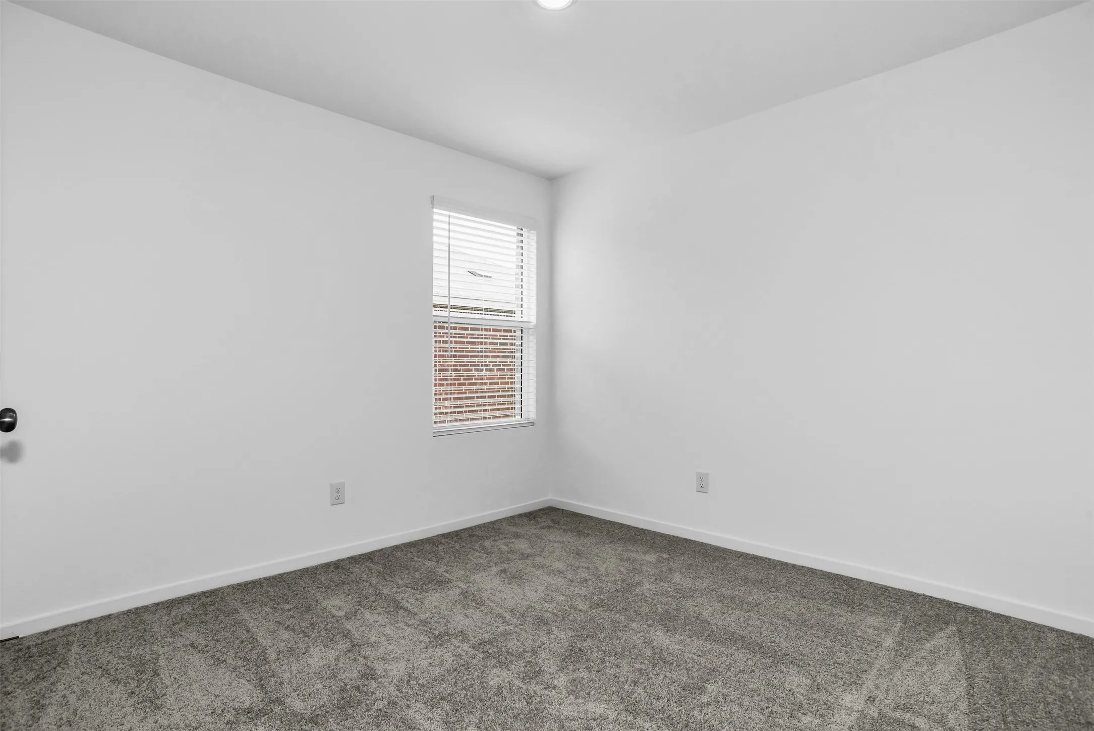 Spare room featuring carpet flooring and baseboards