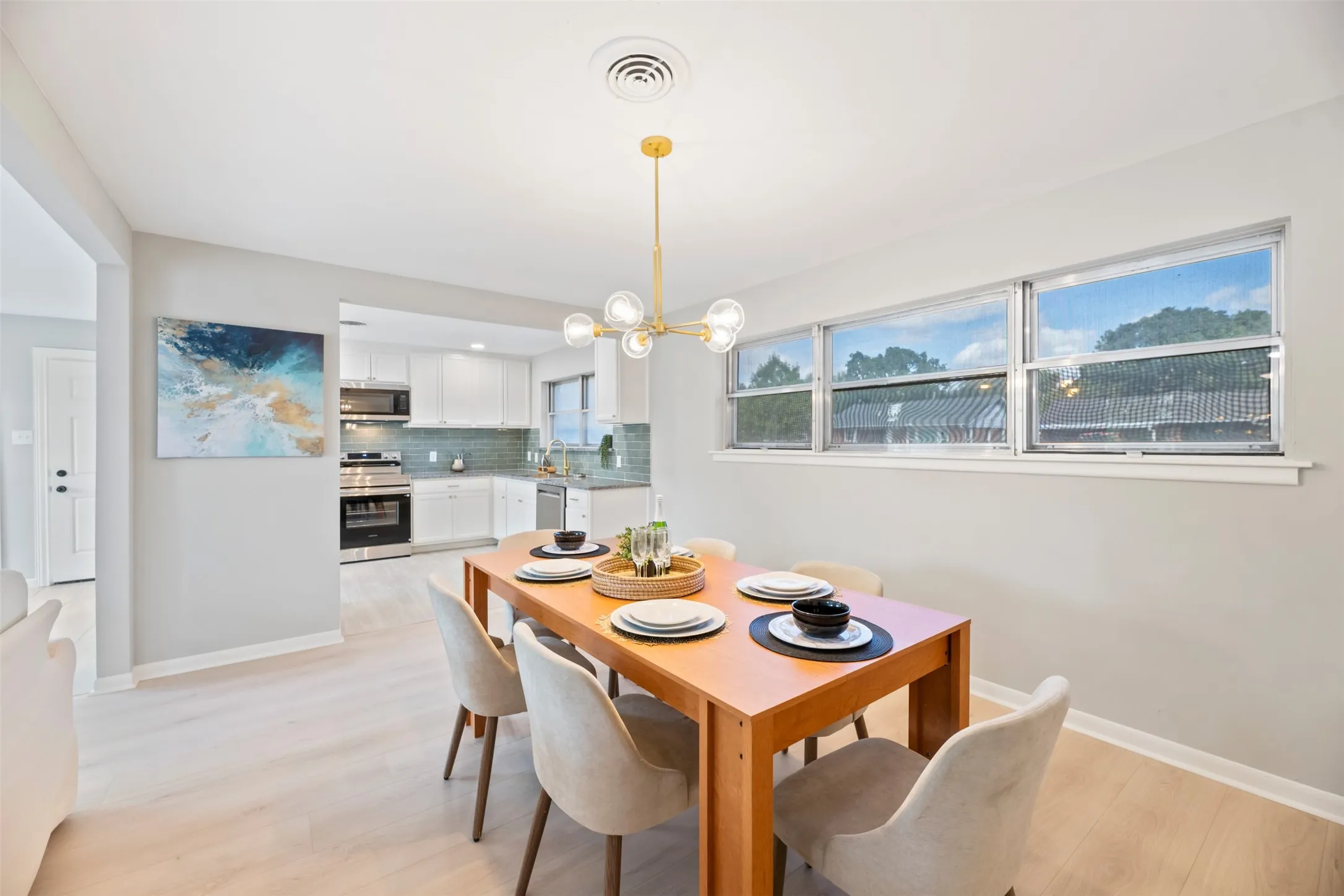 Dining room with new chandelier flows into the kitchen and the living room