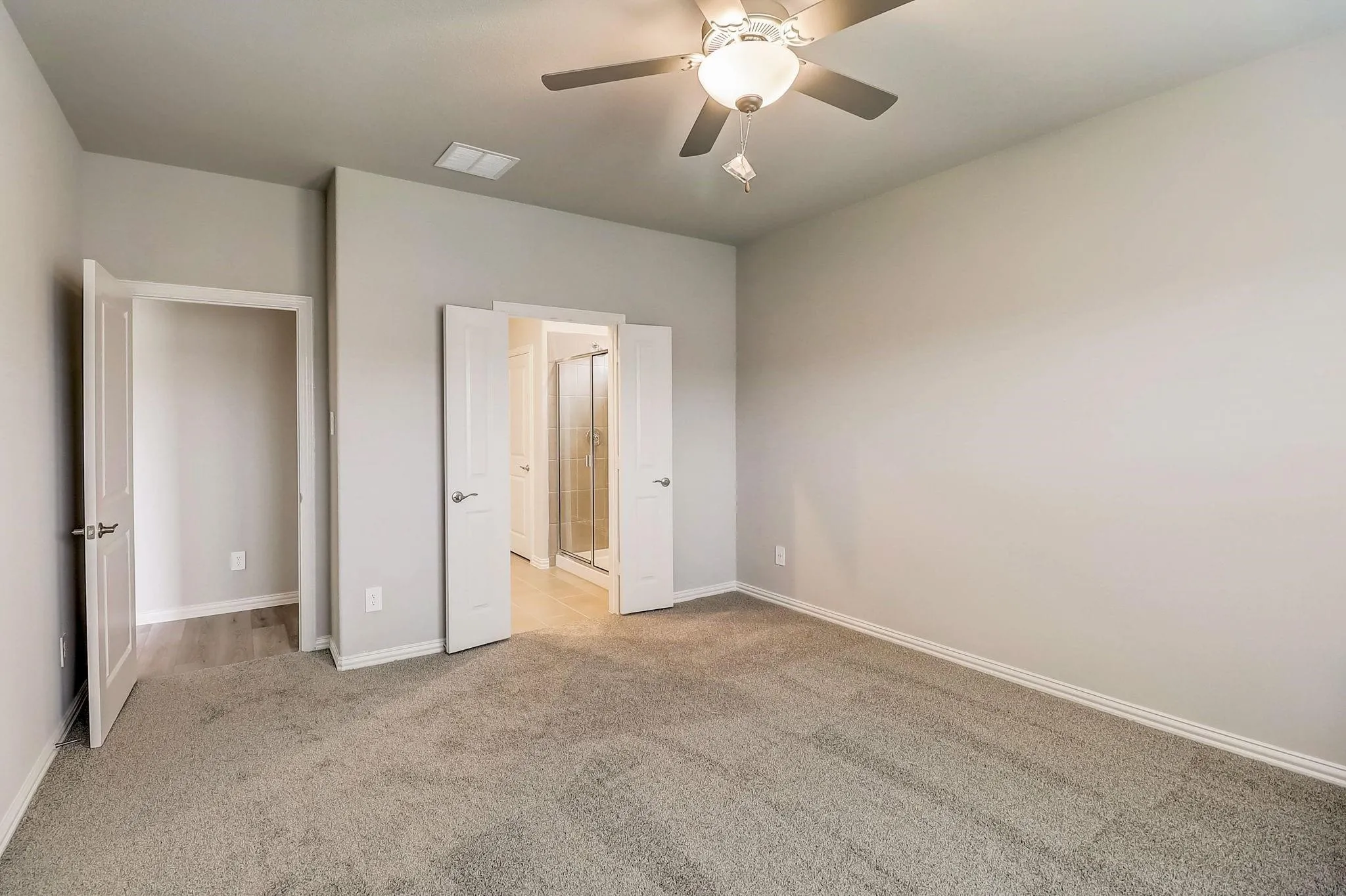 Expansive room featuring plush carpeting, a ceiling fan with integrated lighting, and light-colored walls