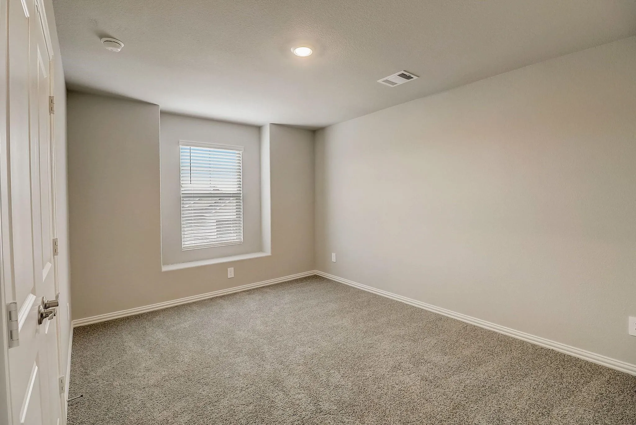 Plush carpet flooring, recessed lighting, and a single window with blinds