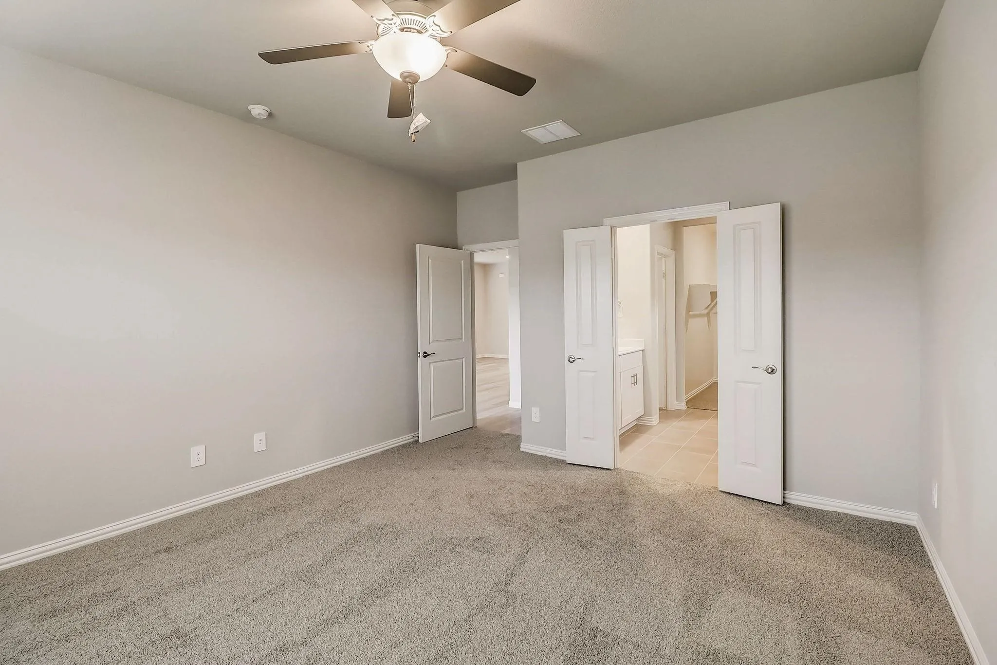 Carpeted room with ceiling fan and overhead light fixture