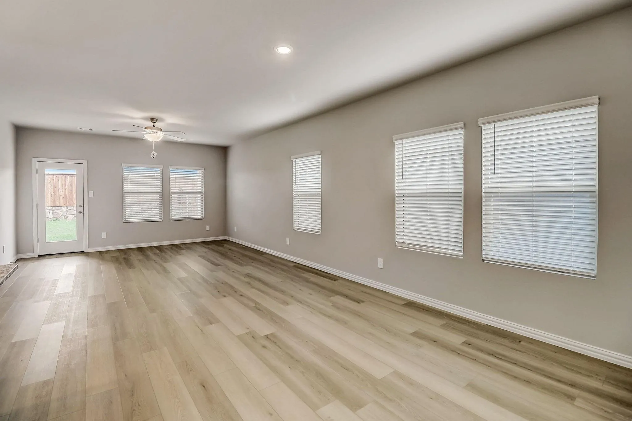 Spacious room featuring wood-finish flooring, ample natural light from multiple windows, recessed lighting, and a ceiling fan