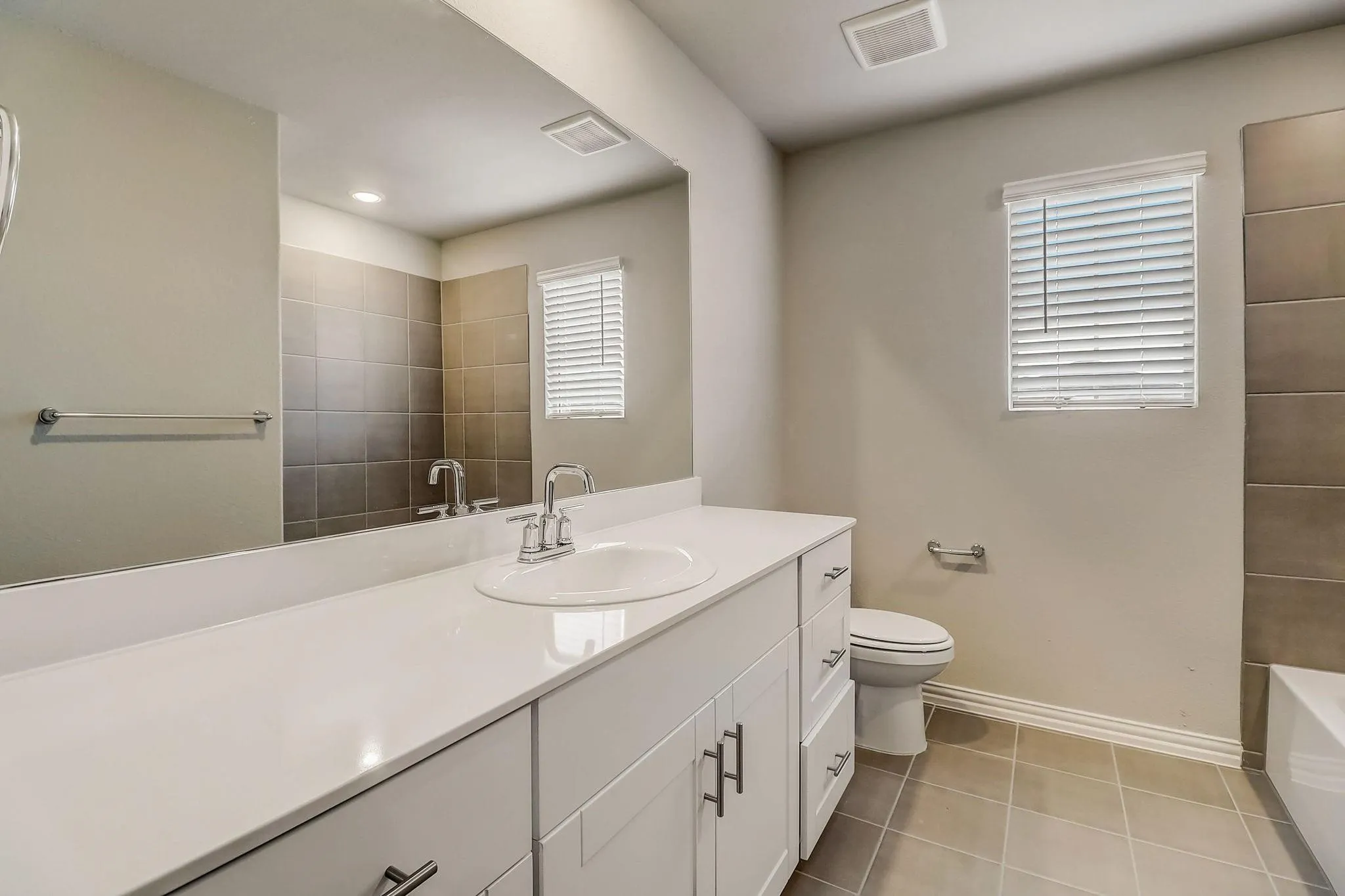 White vanity with chrome hardware, an undermount sink, and a white countertop