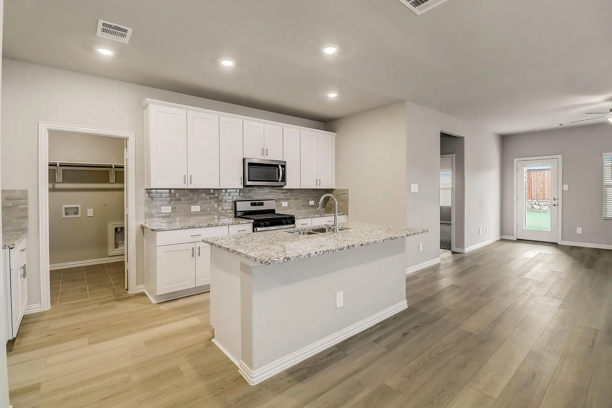 Kitchen featuring white cabinetry, stainless steel appliances, a tile backsplash, and a central island with a sink