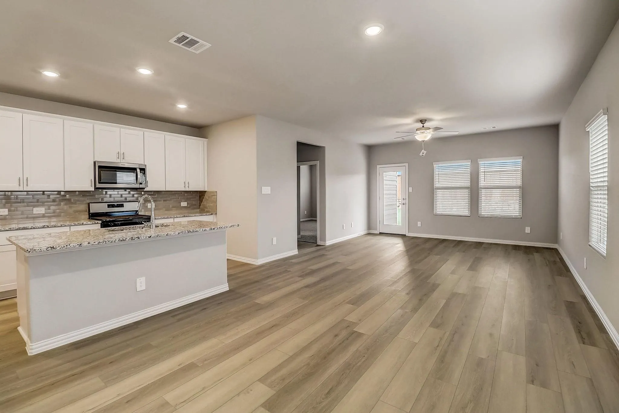 Open-concept living area featuring wood-finish flooring, recessed lighting, and a ceiling fan