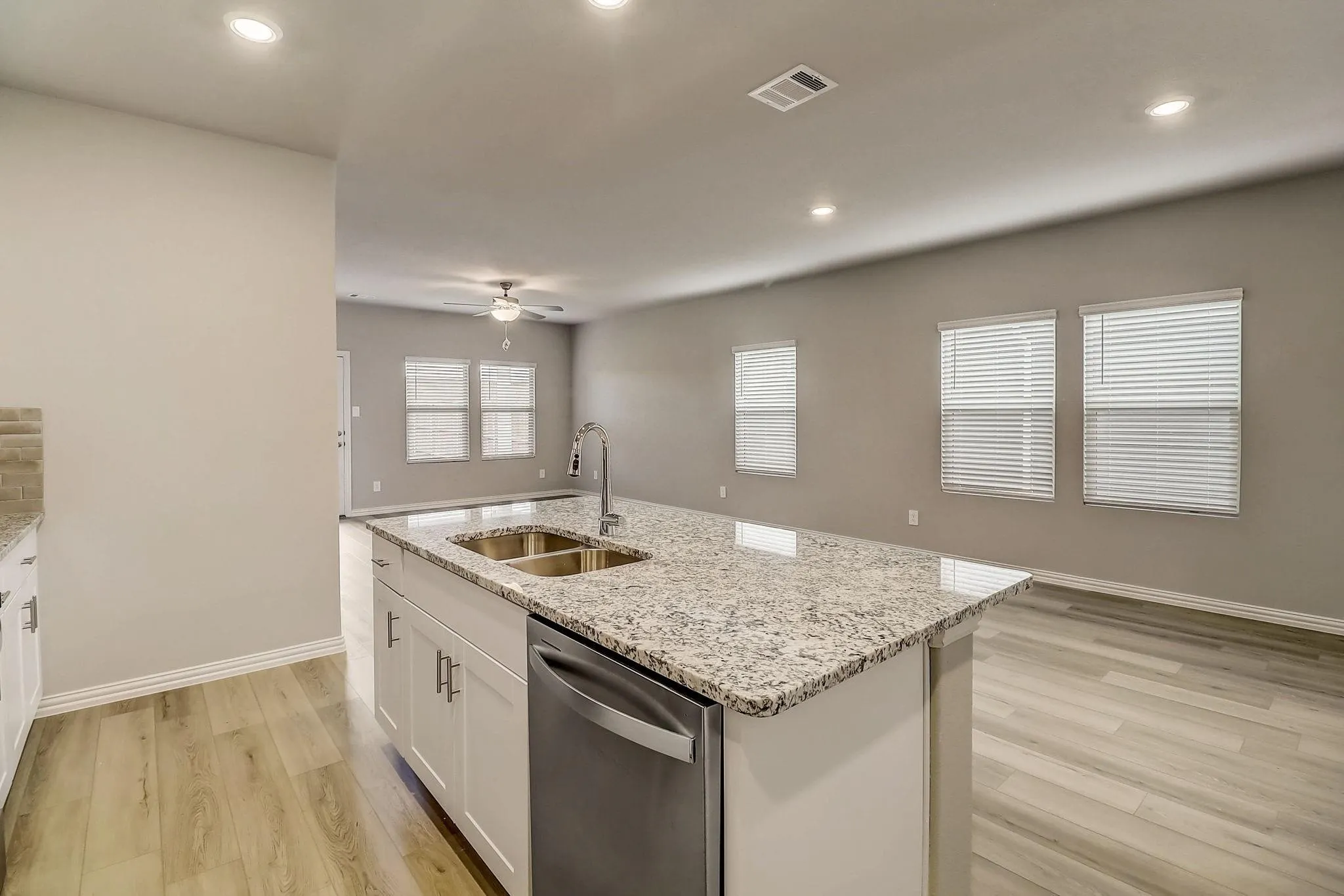 Kitchen island with granite countertop, double stainless steel sink, and integrated dishwasher