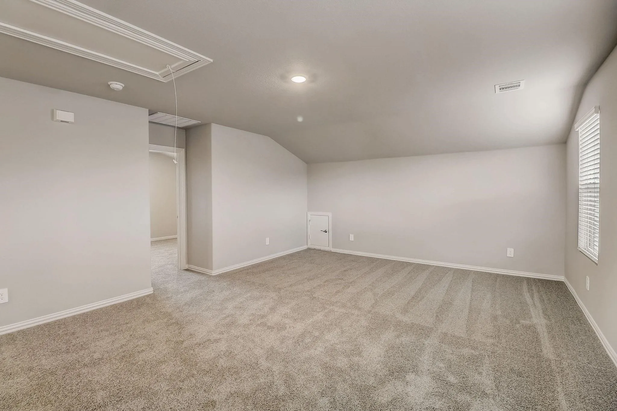 Spacious carpeted room with sloped ceilings, recessed lighting, and window blinds