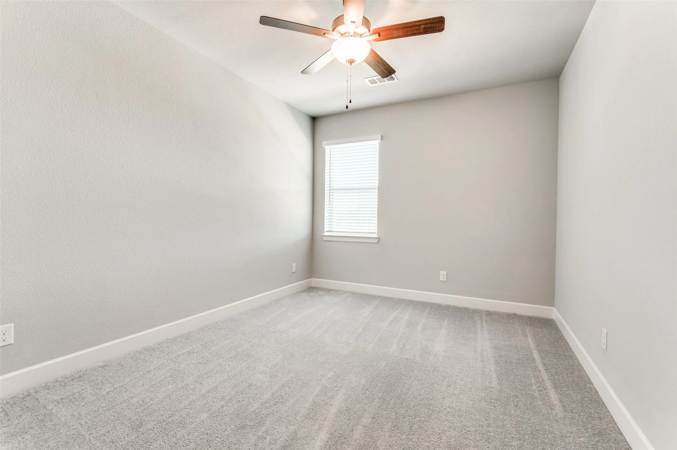 Neutral-toned wall finishes, light gray carpet, and a ceiling fan with integrated lighting