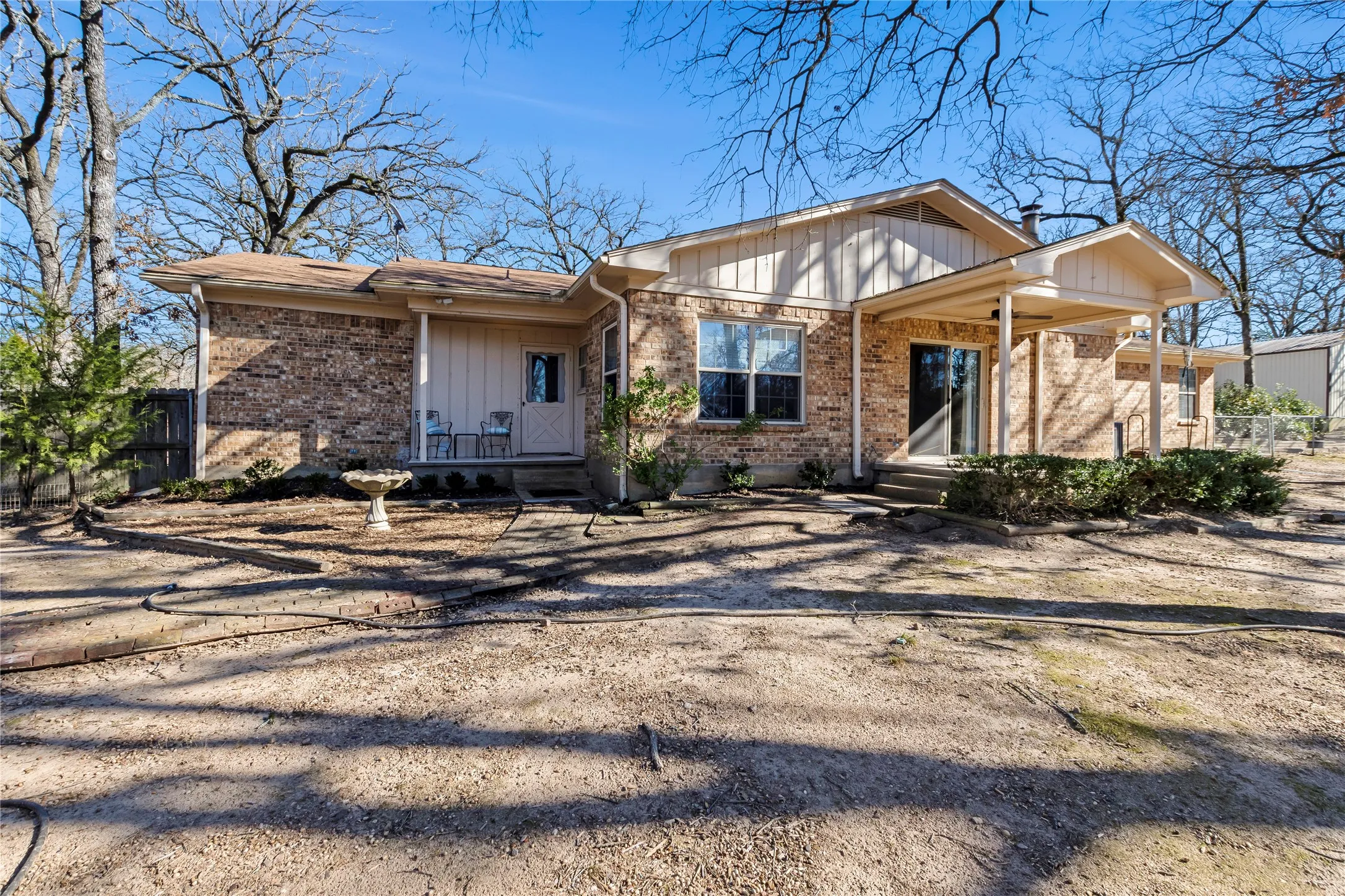Covered back porch overlooks fenced yard and large pond on a total of 2.9 fenced acres--gorgeous trees!