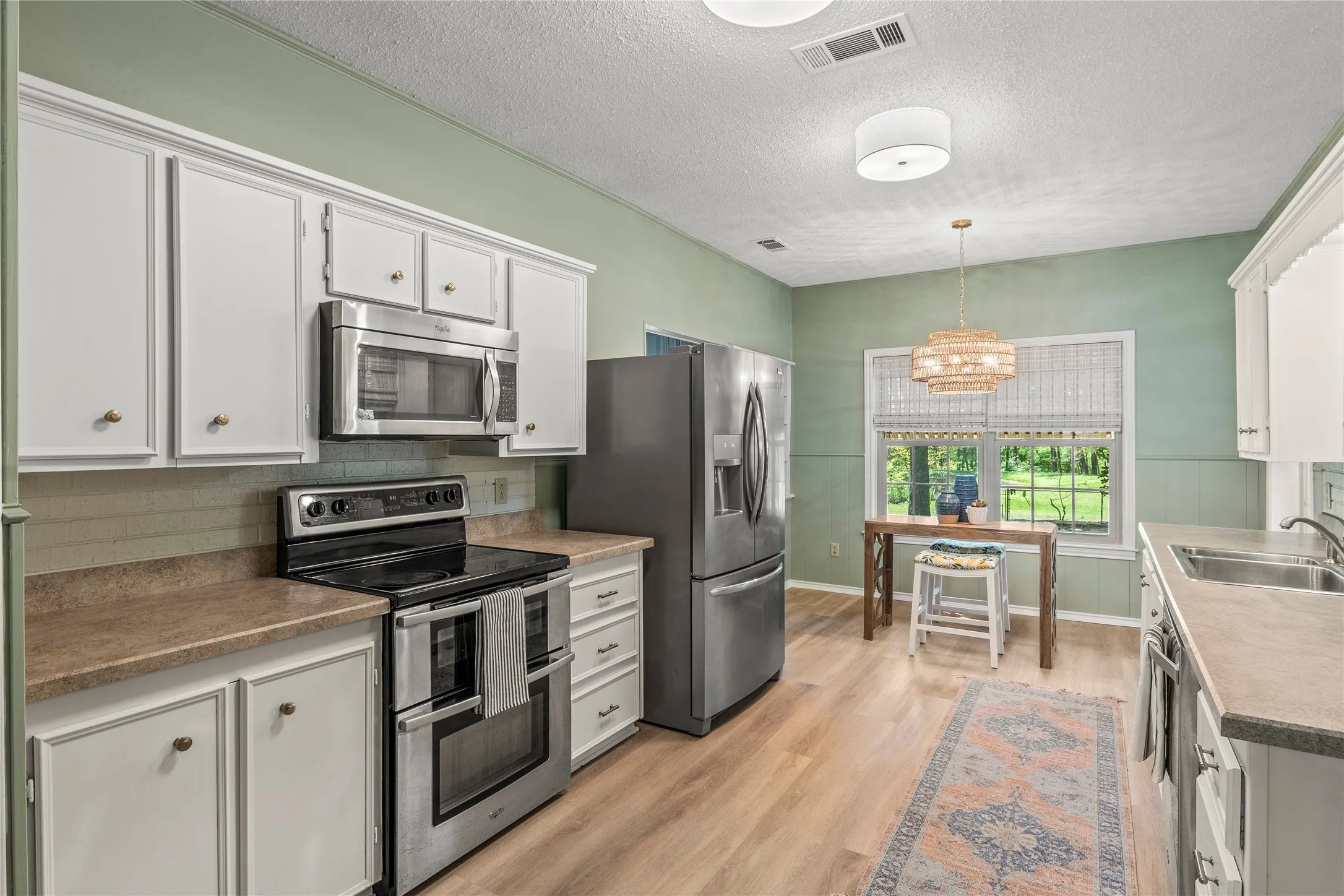 Freshly painted kitchen features new stainless steel appliances, sink, fixtures, and luxury vinyl plank floor.