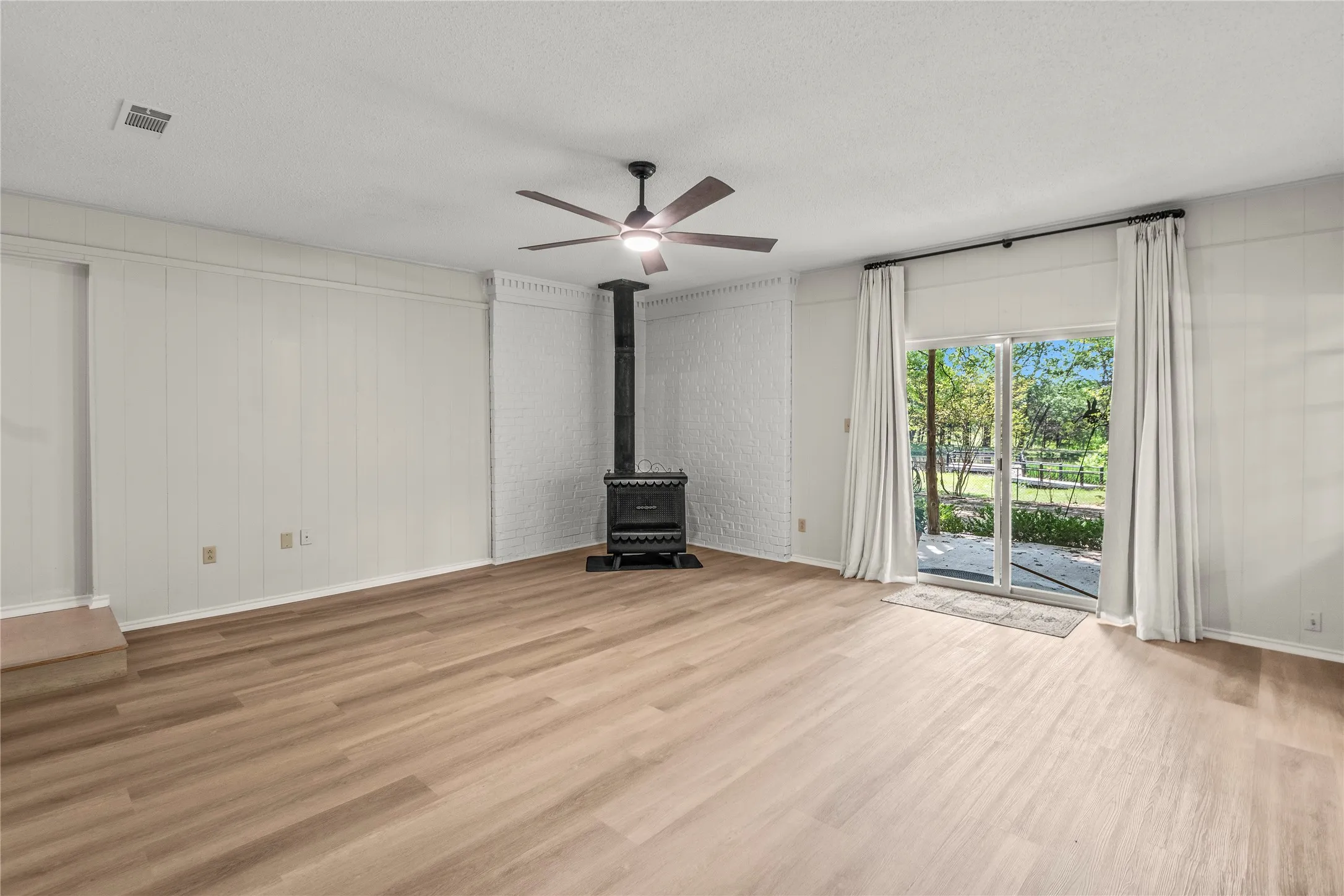 Spacious family room freshly painted with  with new luxury vinyl plank flooring, new fixtures andwood burning stove.