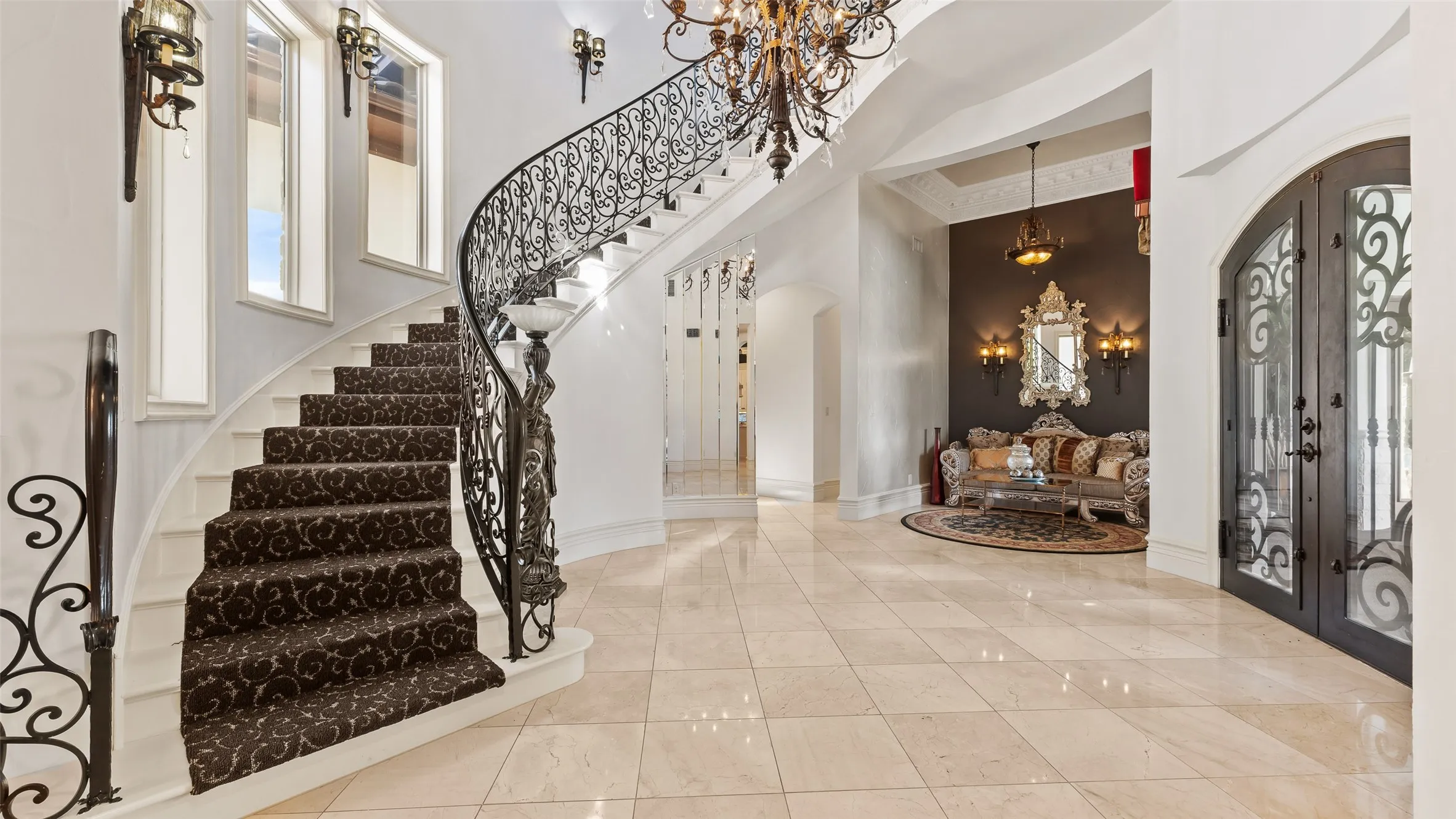 Sweeping staircase with ornate wrought iron railing, arched doorways