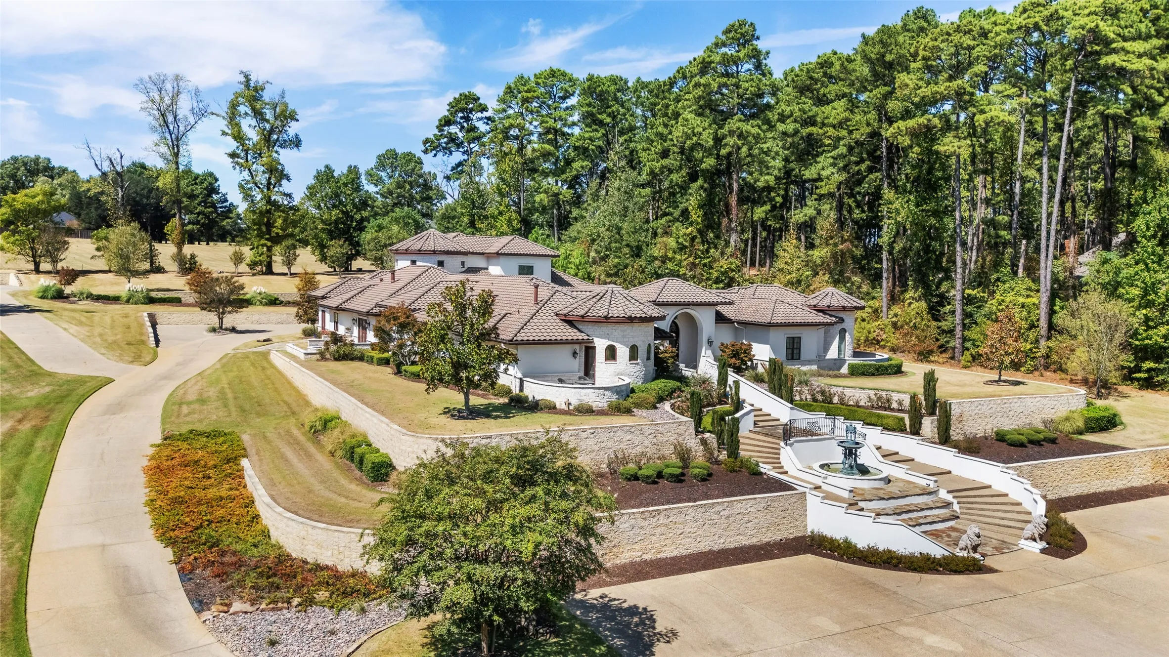 Multi-level residence featuring a terraced facade, barrel tile roof, and a grand bifurcated staircase with a central fountain