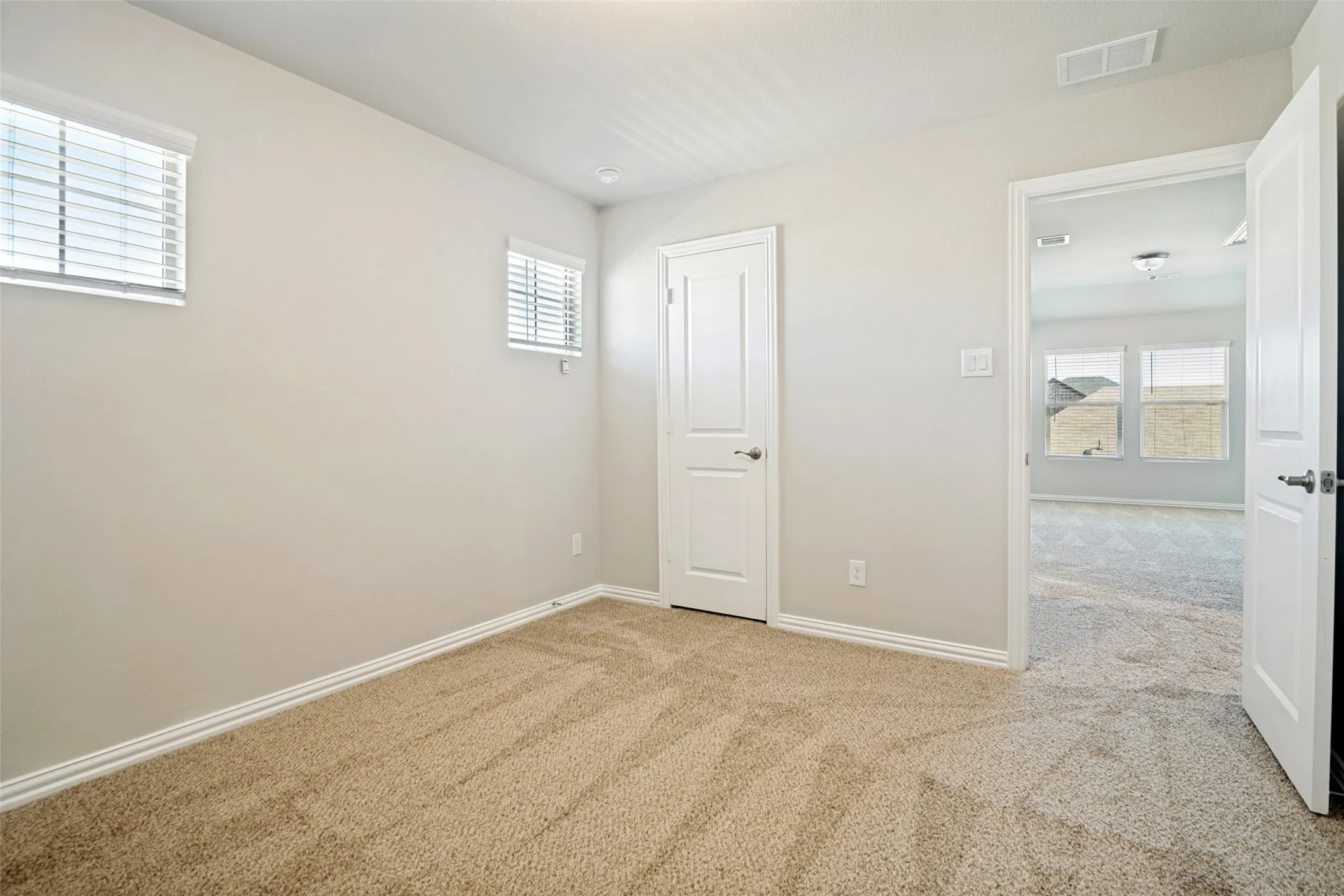 Neutral wall finishes, recessed lighting, two windows with blinds, and carpeted flooring